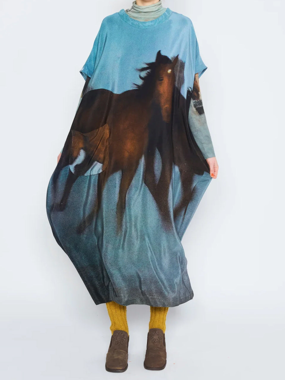 Anntian Overdress in Print H worn with the side pulled outward, showing the generous draped volume and oversized horse graphic.