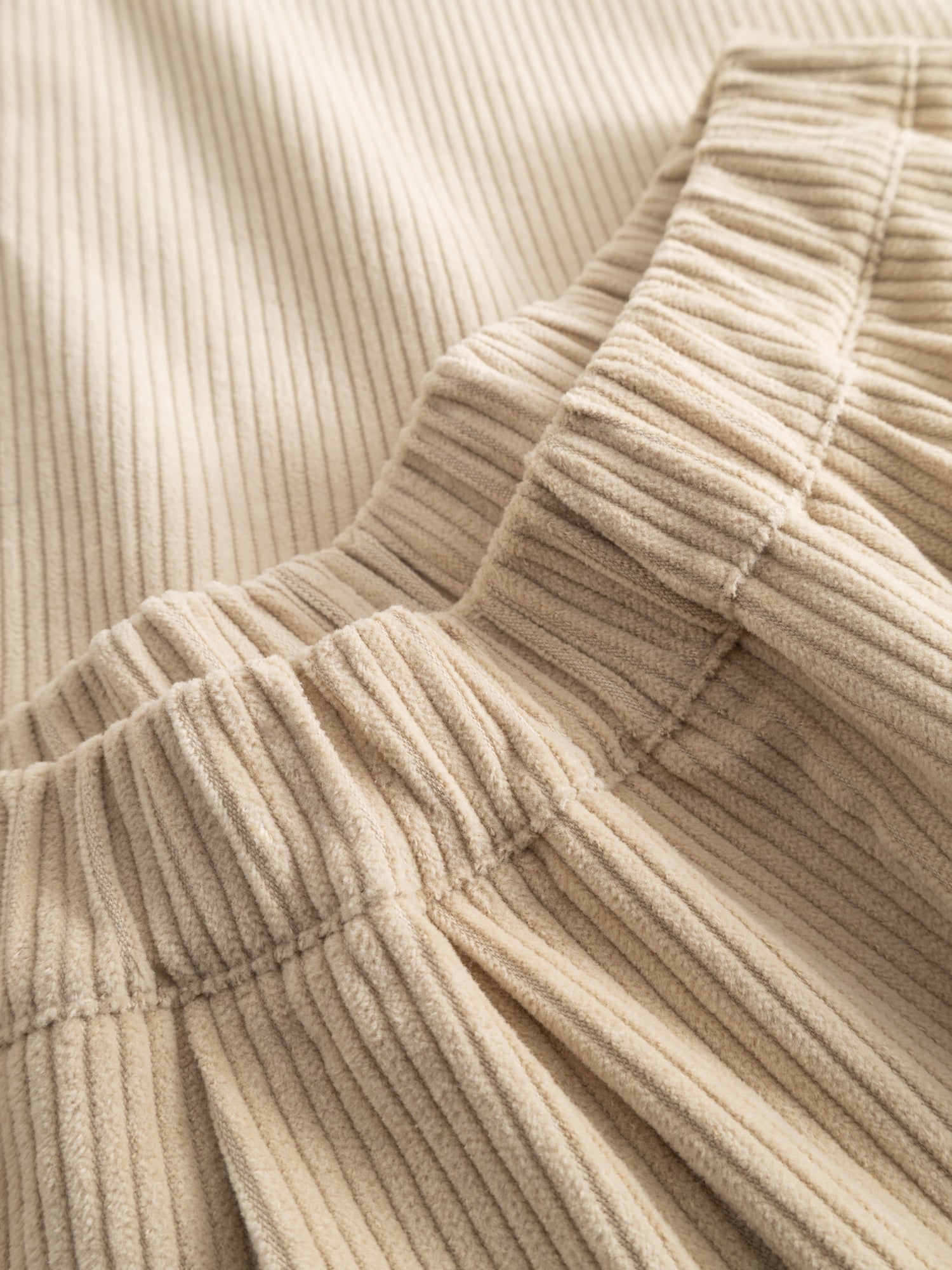 Close-up of the Black Crane Corduroy Wide Pants showing the off-white corduroy texture and the brand label at the waistband.