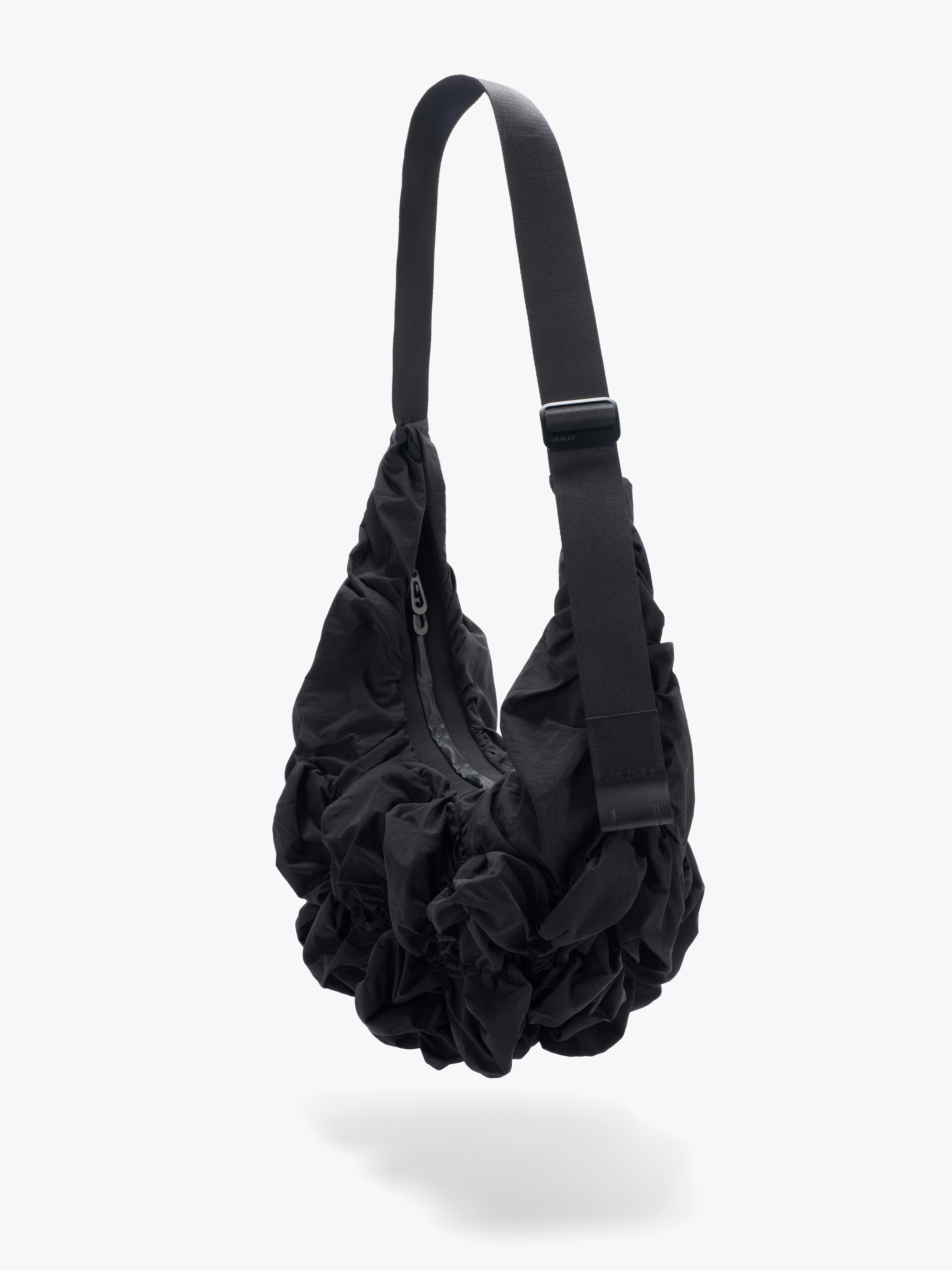 Côte&Ciel Hyco S Otra Gathered crossbody bag in black, diagonal view highlighting ergonomic shape and textured ruched nylon material.
