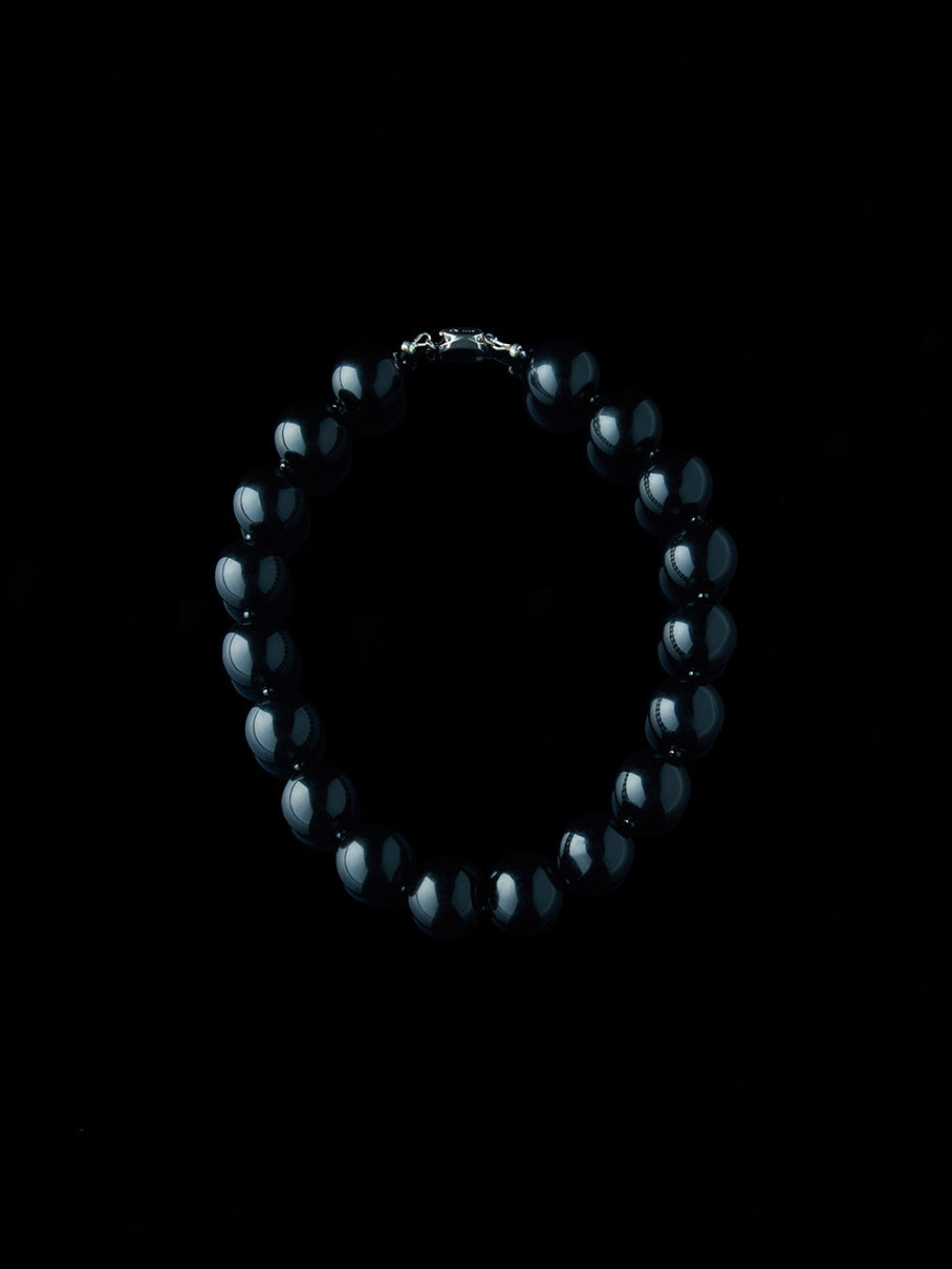 Black and round obsidian necklace with silver clasp from De Silang on a black background