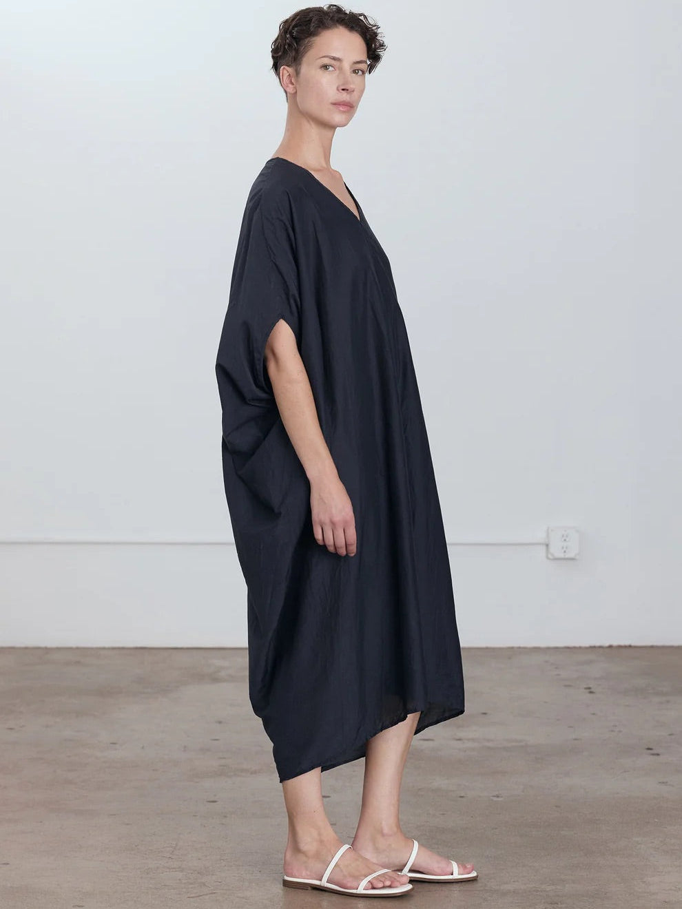 Black Crane Draped Dress in Faded Black - side view on model showing dolman sleeve and voluminous draped silhouette
