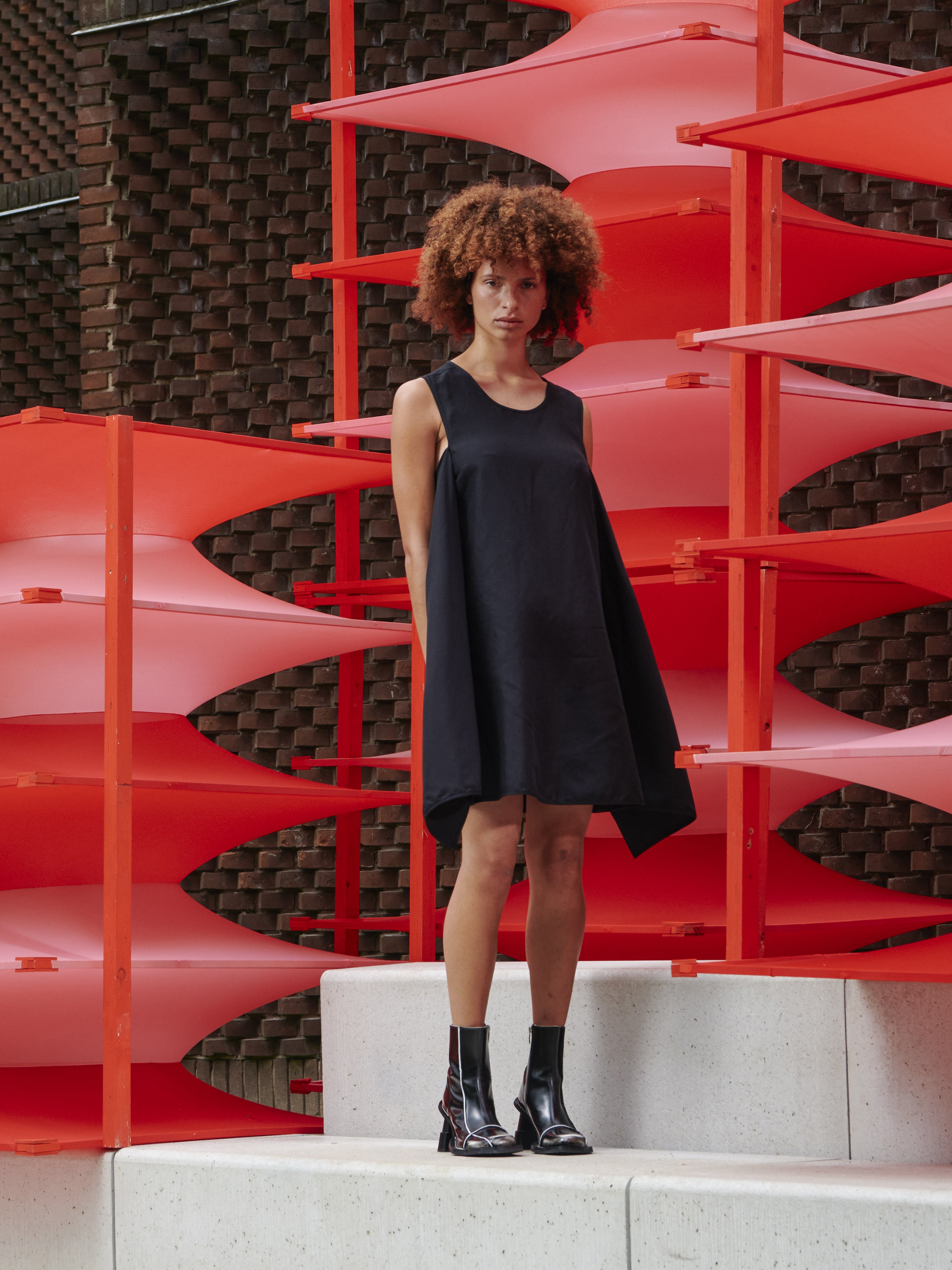 Model wearing Henrik Vibskov Beetle Dress in black, back tie styling, sleeveless silhouette, showcasing sculptural SS26 design.
