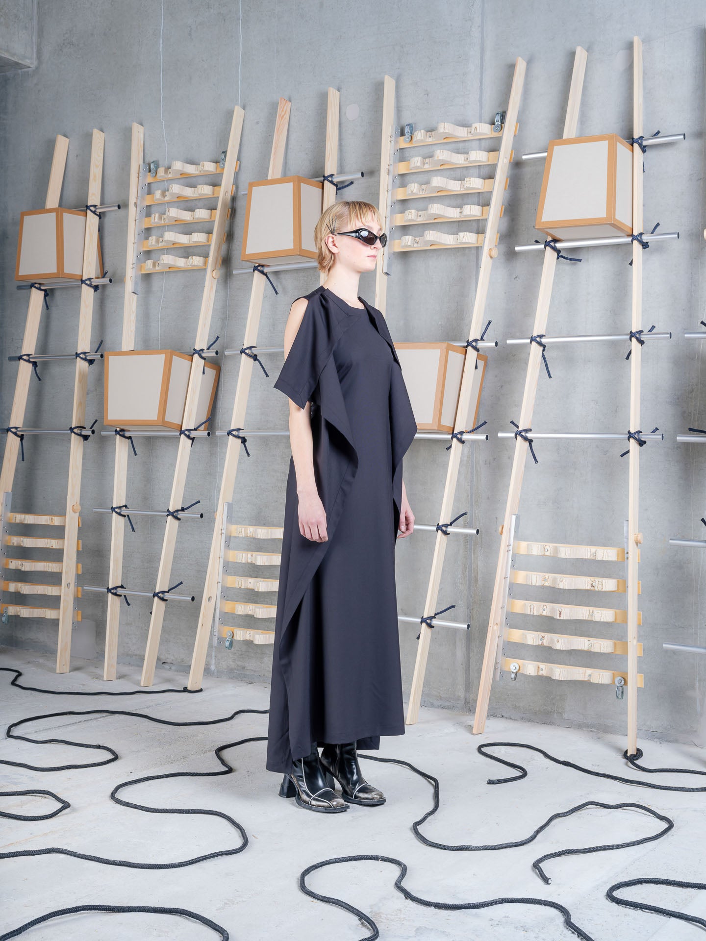Model wearing the Henrik Vibskov Blanket Dress in black, side view showing the draped shoulder detail