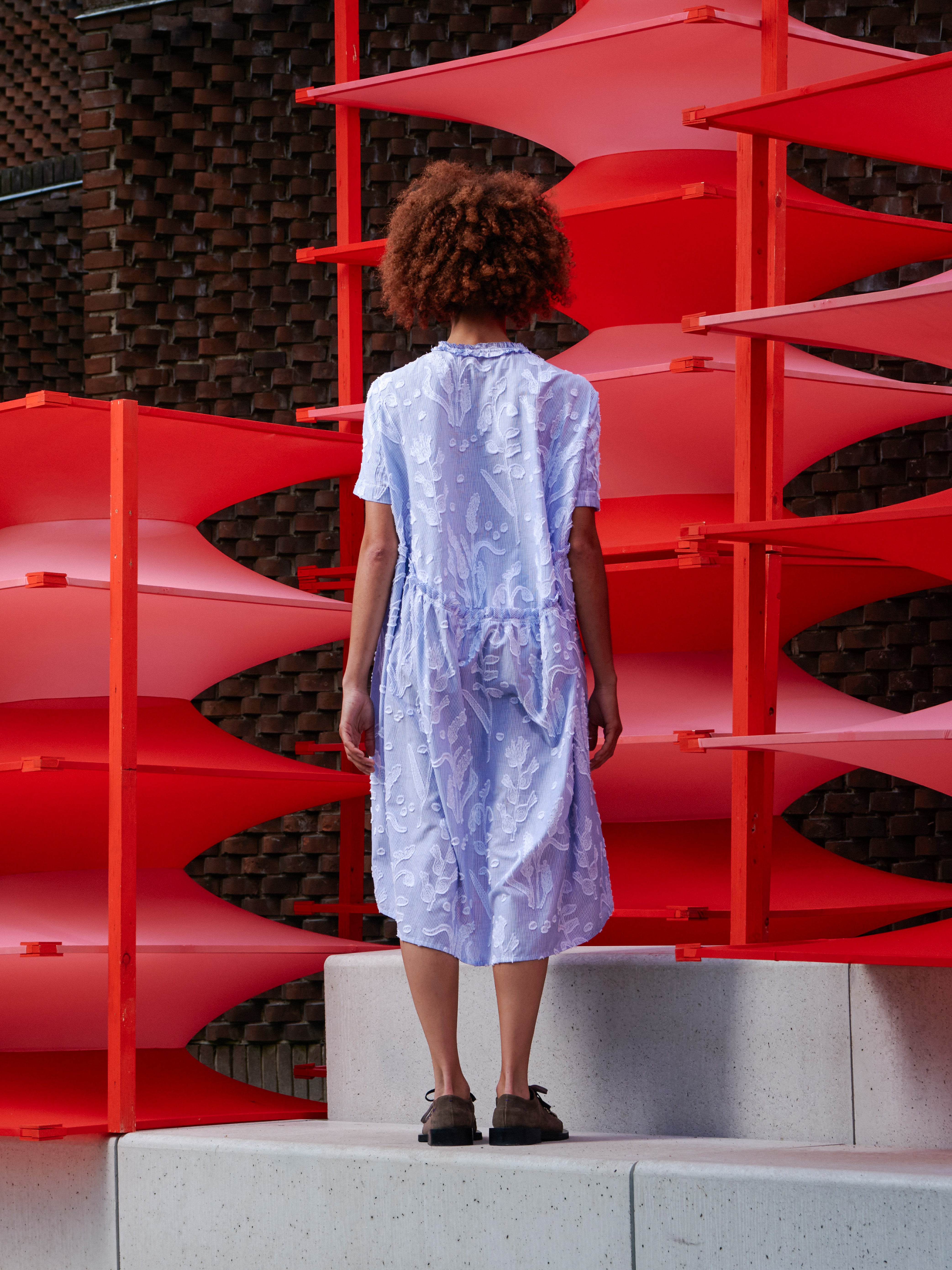 Back view of the model wearing the Bon Chalant Dress, showcasing the oversized shape and elastic ruching throughout.