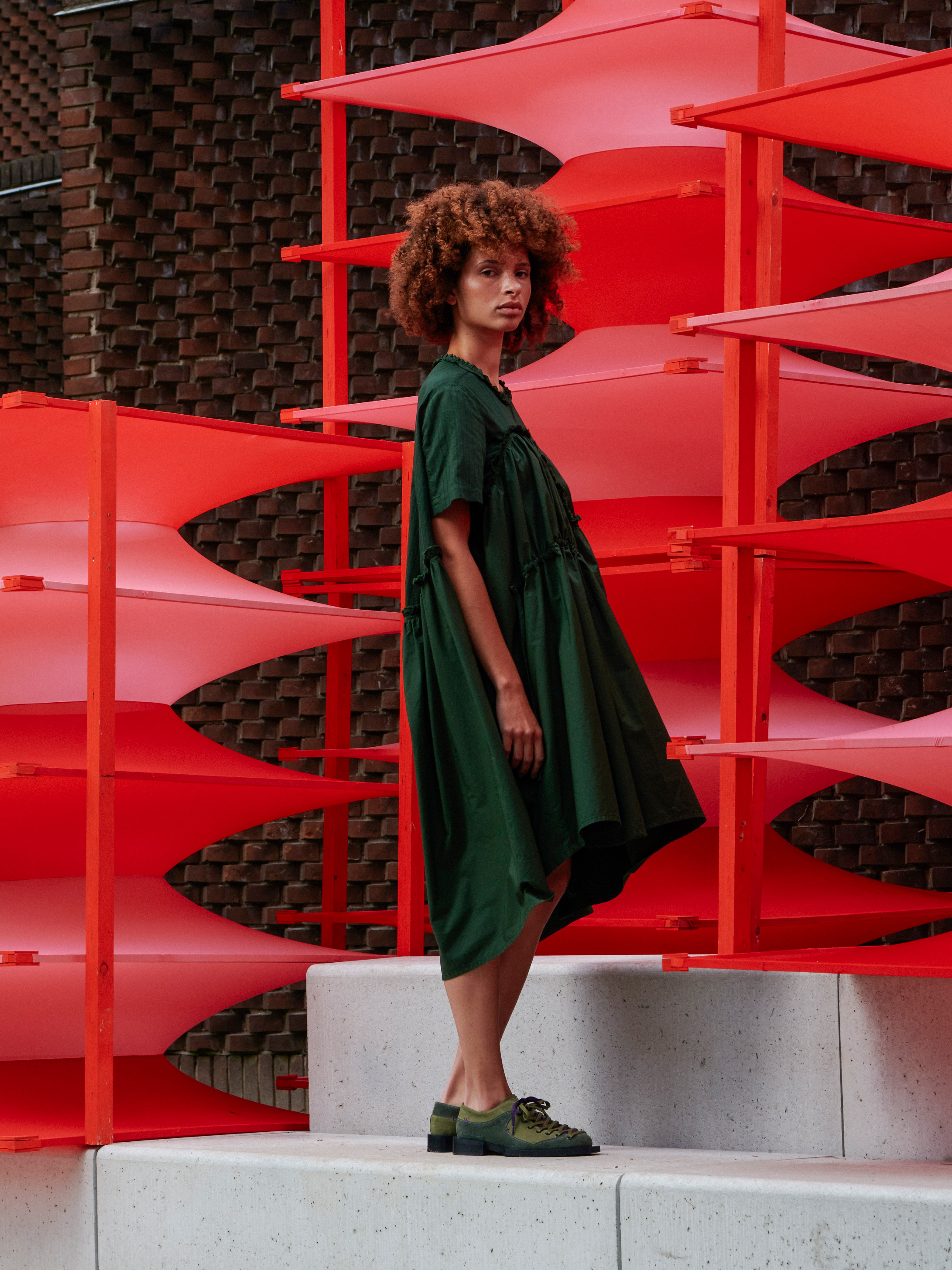 Side view of a model wearing the Bon Chalant Dress, highlighting the sculptural volume and textured ruching.