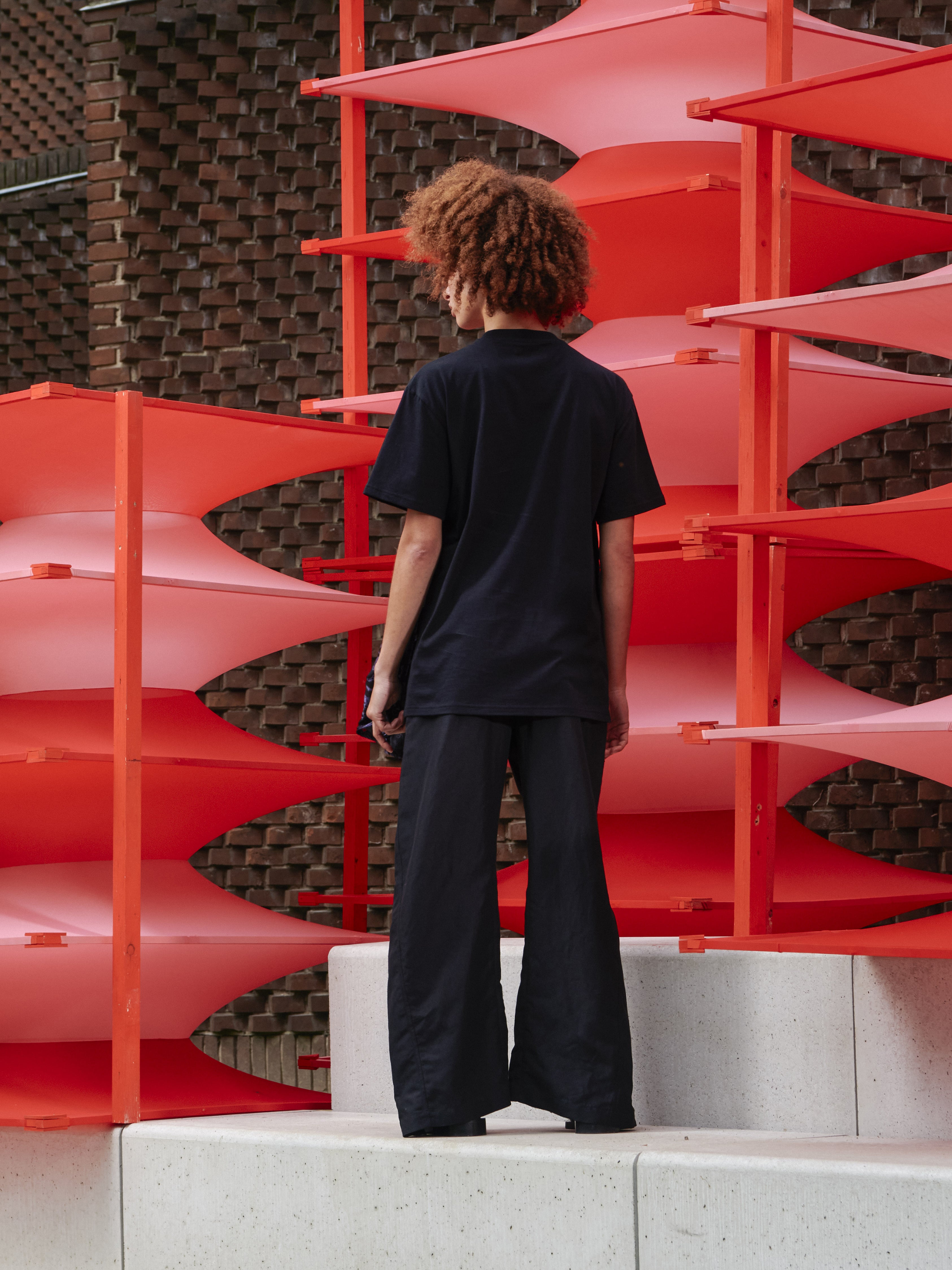 Back view of model wearing Henrik Vibskov Bon Chalant Tee in black, highlighting loose sculptural fit, gentle volume, and floral print detail.