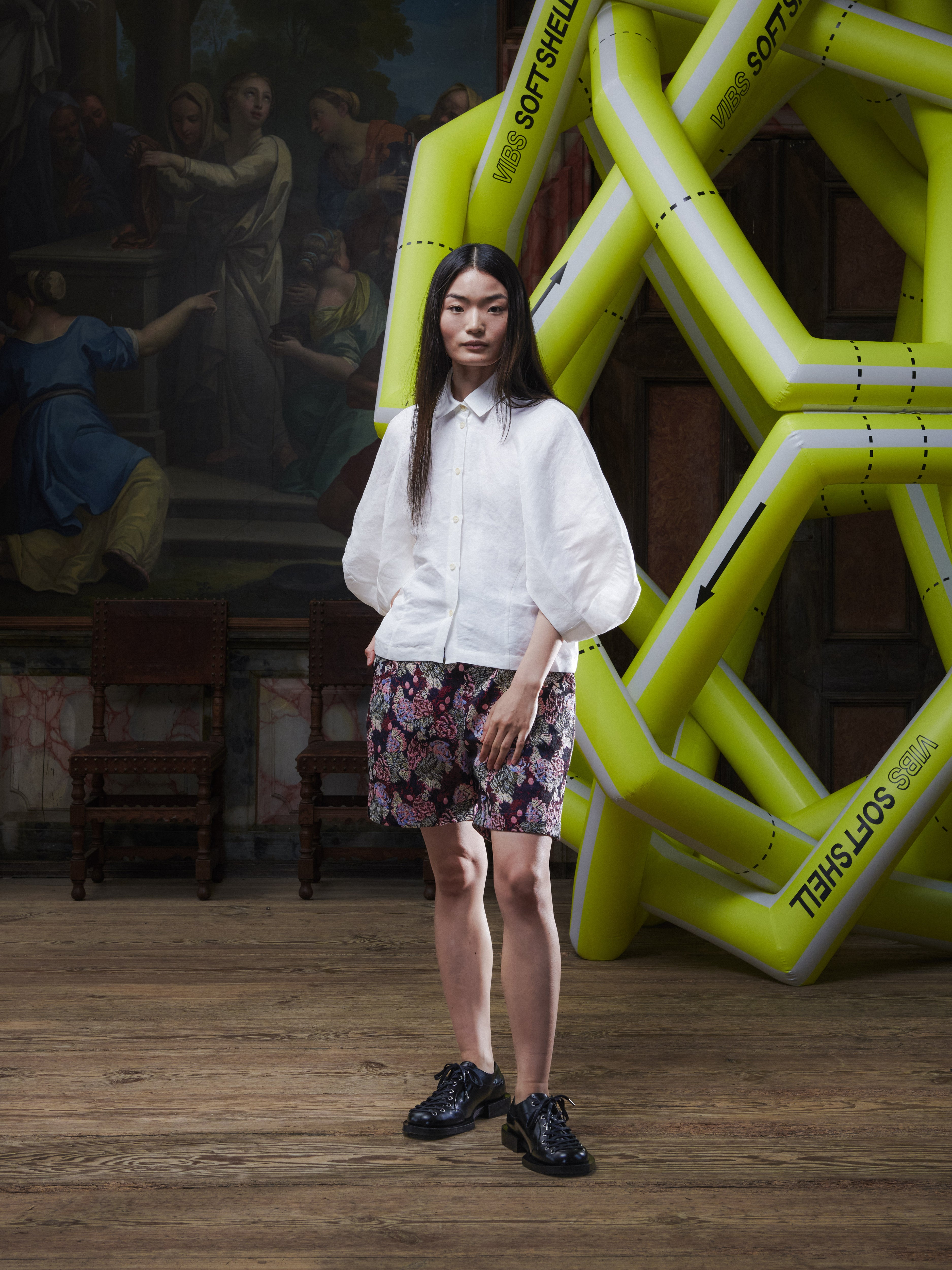 Front view of the female model wearing the Case Shirt in White from Henrik Vibskov Spring/Summer 2026 Studio Collection, displaying the classic collar, 3/4-length raglan sleeves, and buttoned front.