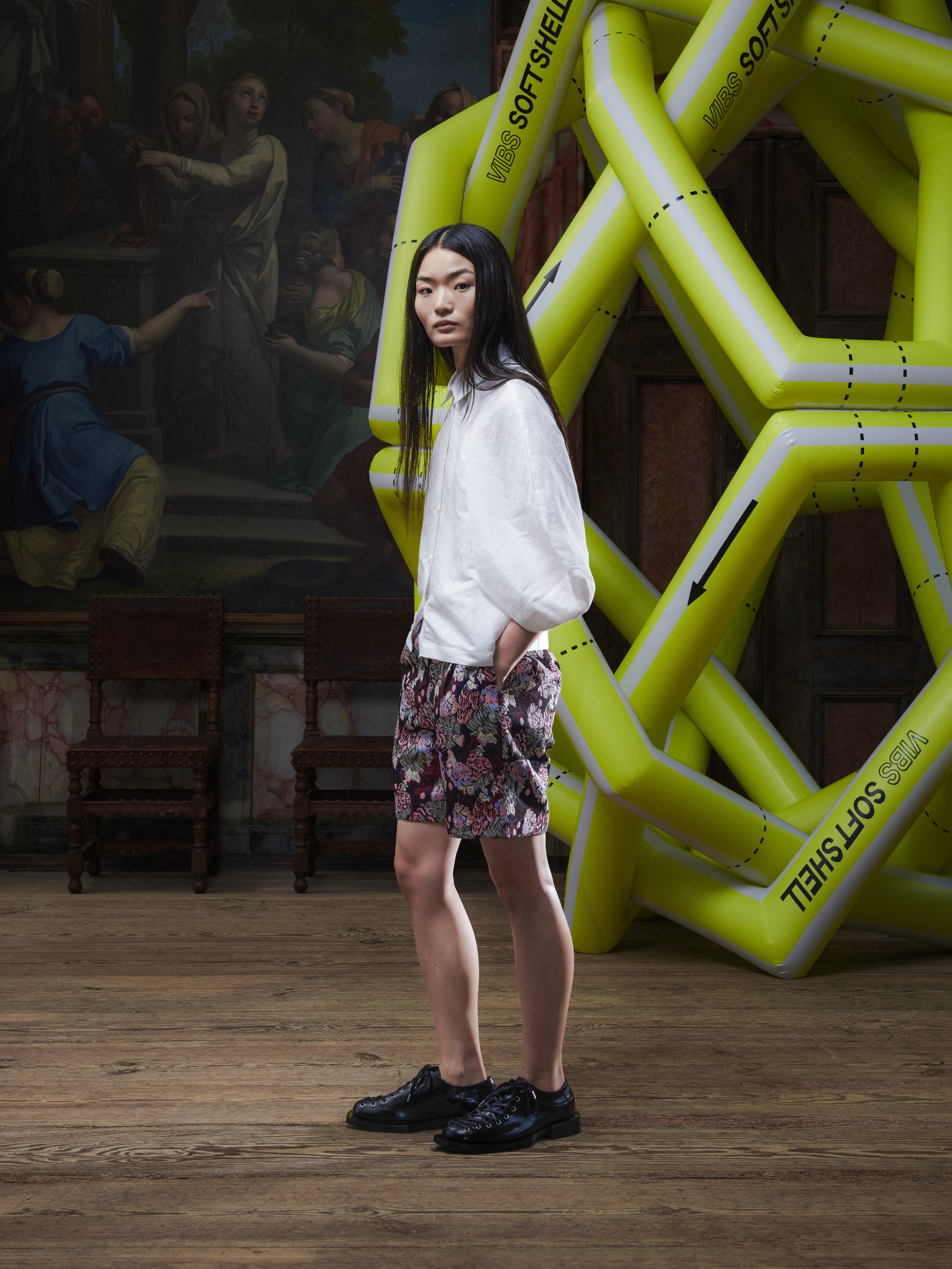 Side view of the female model wearing the Case Shirt in White from Henrik Vibskov Spring/Summer 2026 Studio Collection, showing the relaxed silhouette, raglan sleeve shape, and straight hem.