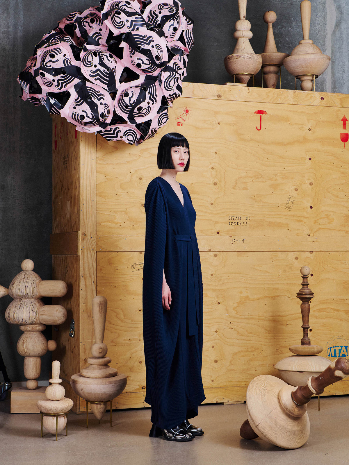 Side view of model wearing Henrik Vibskov Cherry Plisse Kaftan in Dress Blues, showing the cape-style sleeve and flowing pleated shape.
