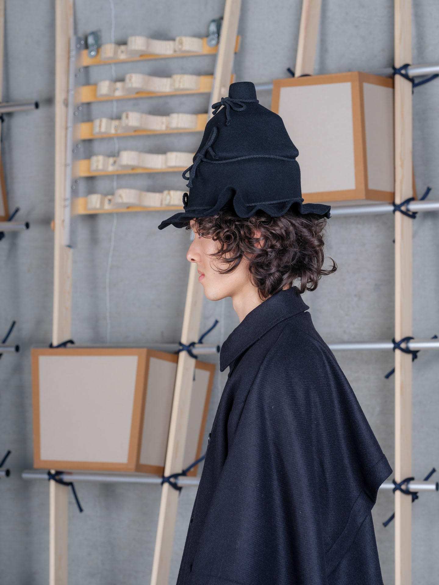 Side view of Henrik Vibskov Christo Wrap Hat in black showing rope tie detail, soft wool finish and undulating brim
