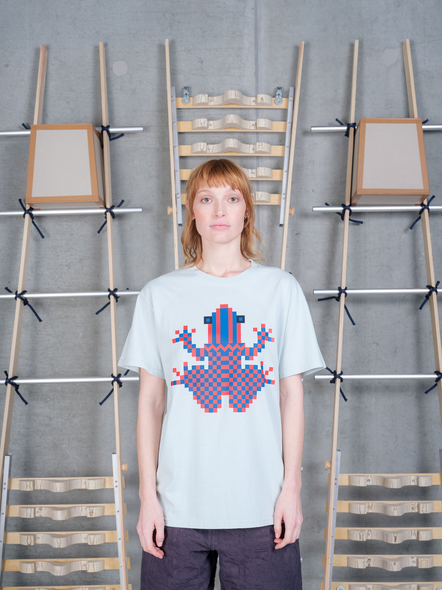 Henrik Vibskov Cross Stitch Tee in Sky Grey worn on model, front view, pixelated frog graphic in blue and coral, crew neck, relaxed fit
