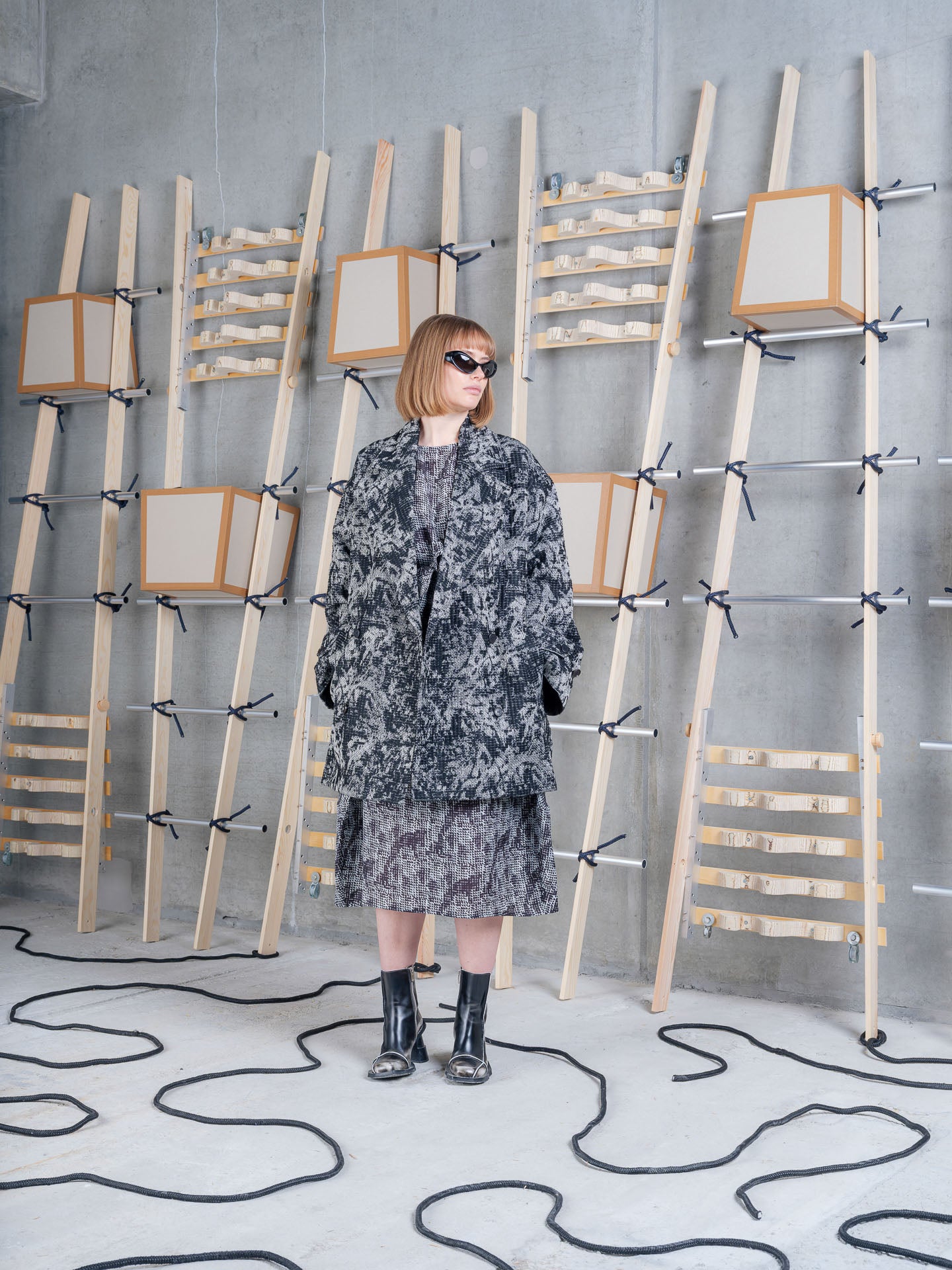 Henrik Vibskov Dimout Coat in Black 3D White worn on model, full-length front view, textured jacquard tweed, notched lapel, double-breasted fastening
