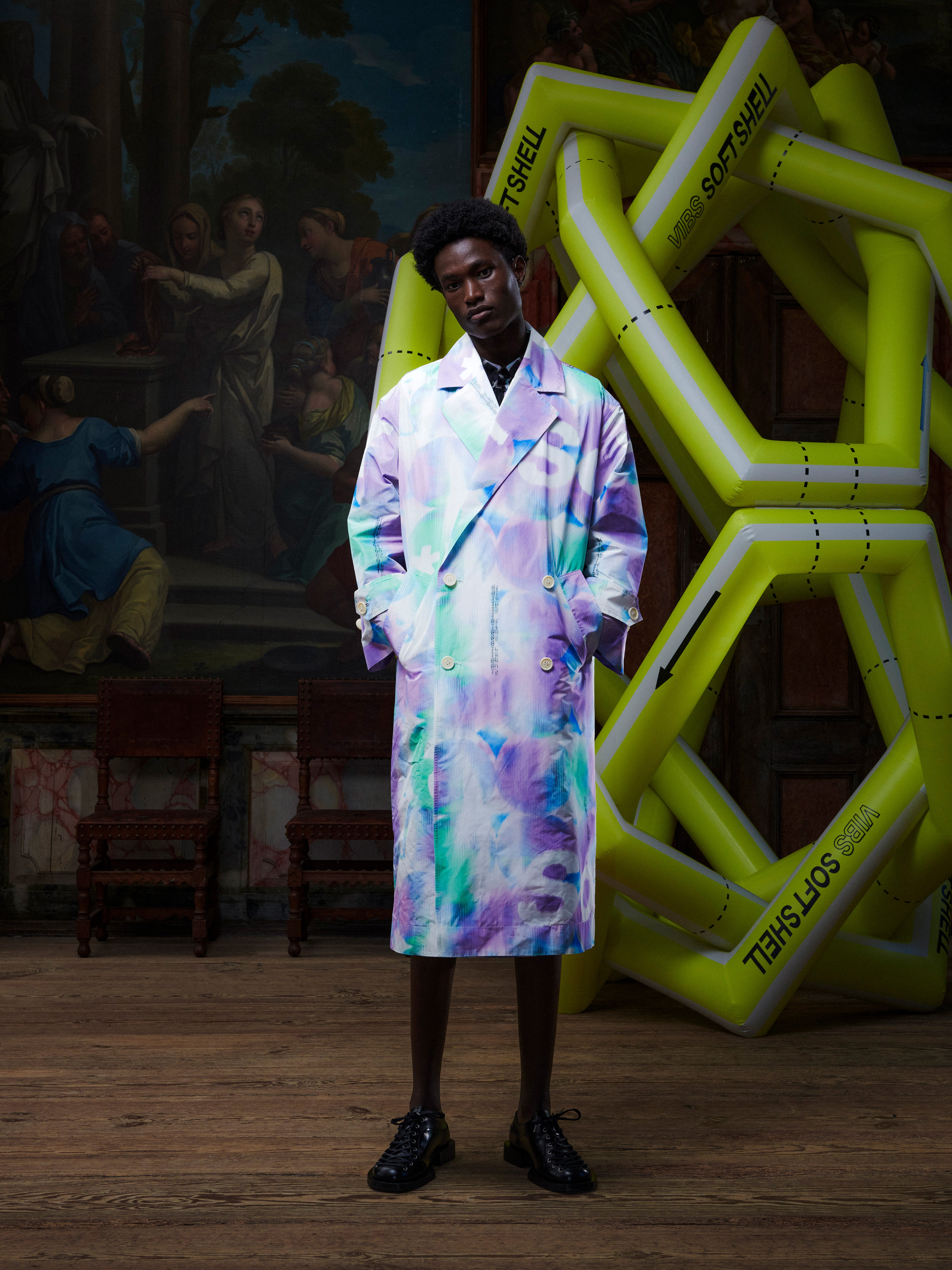 Model wearing the Dimout Long Coat in Bubble Wrap, front view. Model is 181 cm and wears size M/L, showing the bold abstract print, blazer collar, and double-breasted structure.