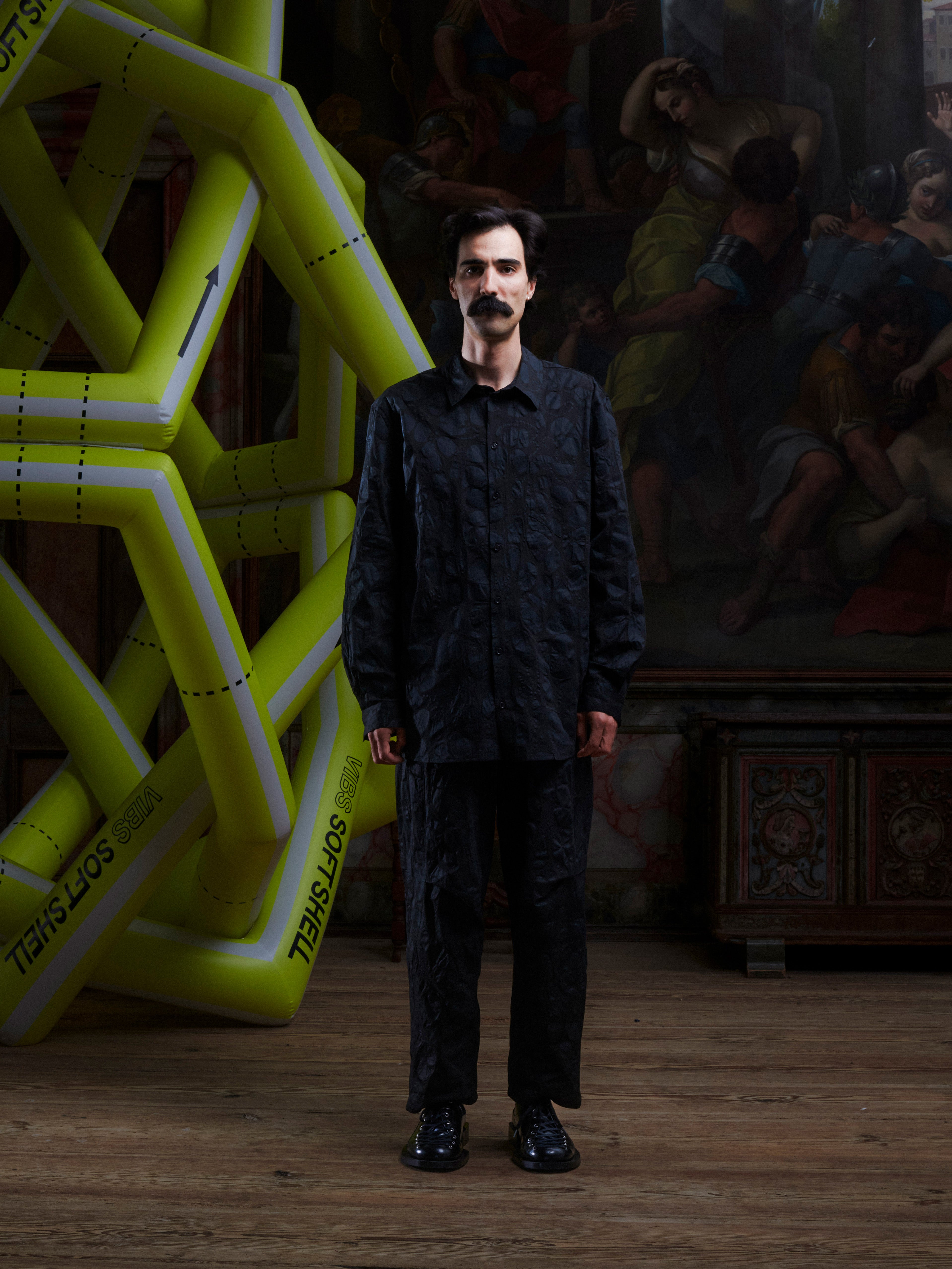 Male model wearing the Drawstring Pants in Black Amulets, front view. Model is 181 cm and wears size XS, showing the relaxed fit, drawstring waistband, and black amulets design.