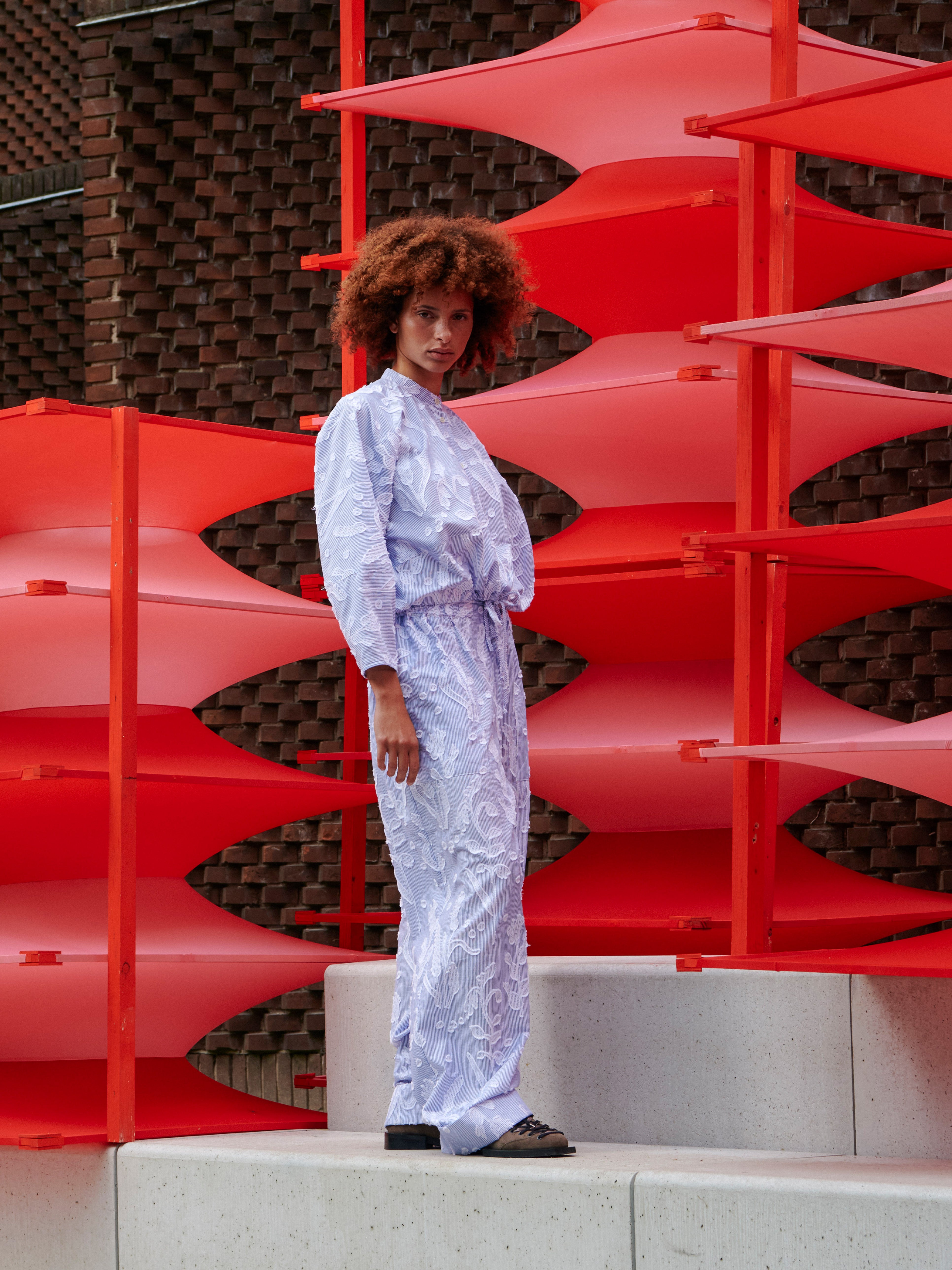 Side view of the model wearing the floral pants, emphasizing sculptural wide legs and side pocket.