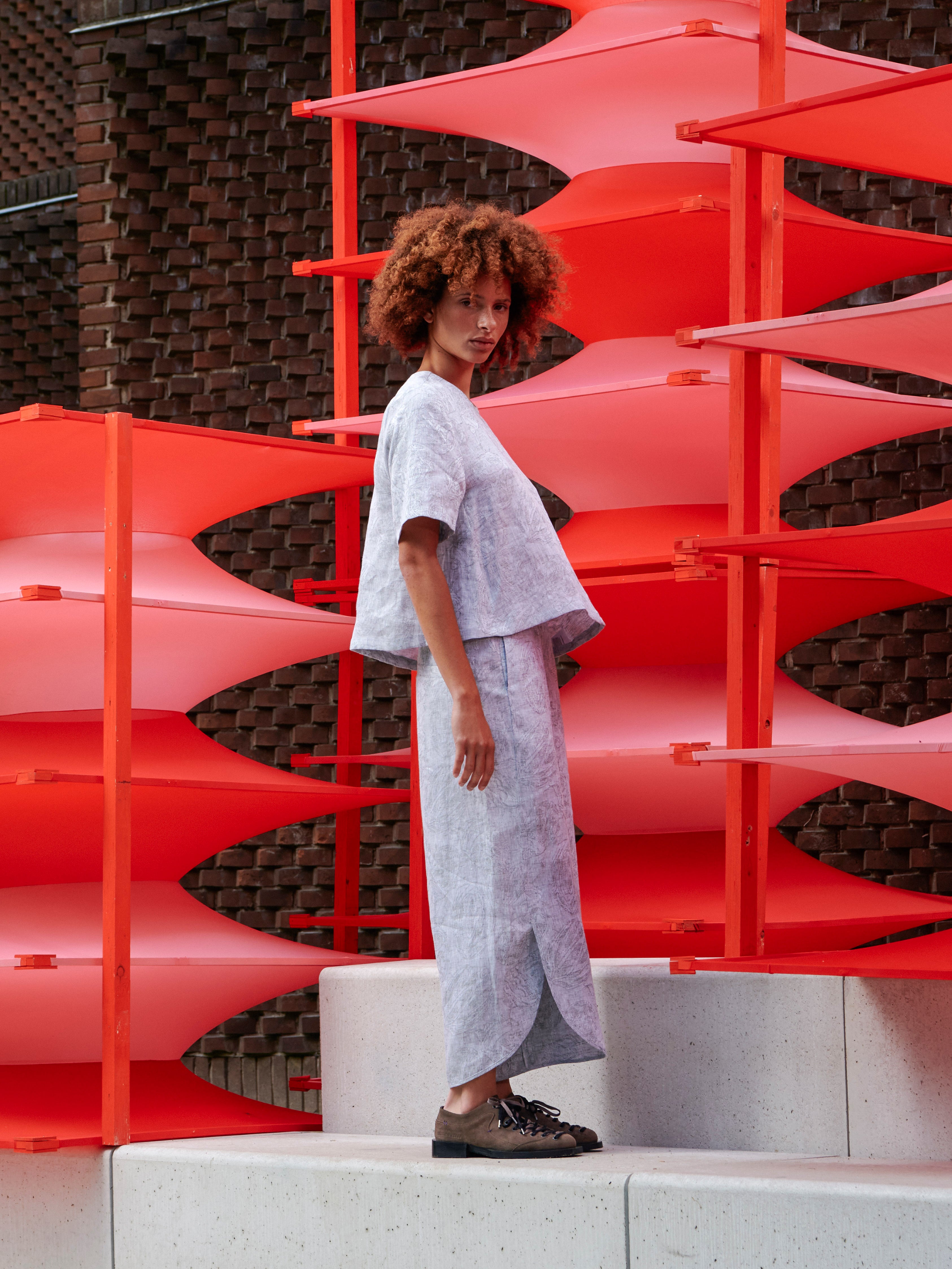 Model wearing the Helmet Top in Bike Helmets grey short sleeve top with straight hem and considered silhouette, side view – Henrik Vibskov Spring/Summer 2026 Key Collection