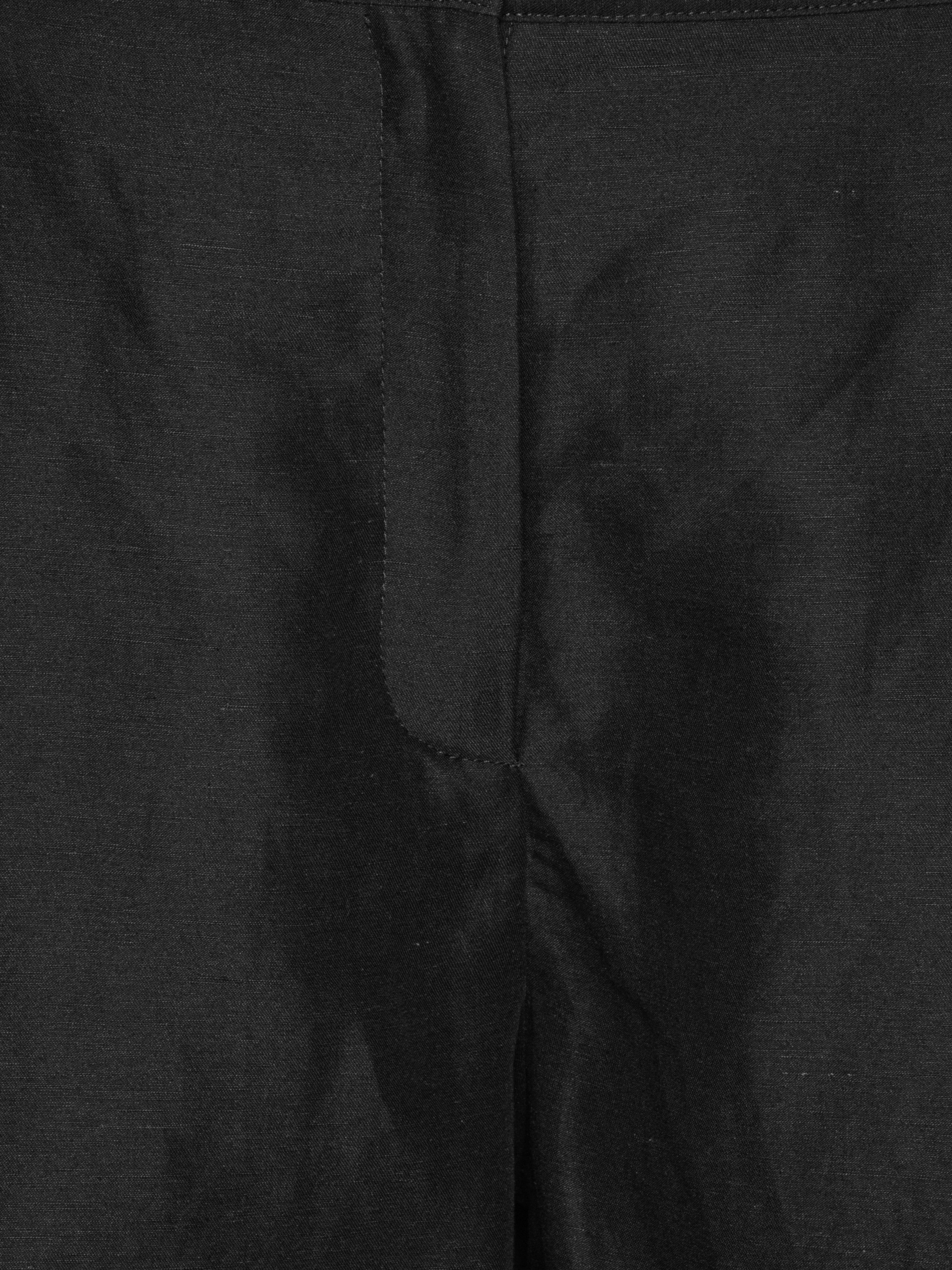 Close-up of the black Tencel-linen fabric highlighting the fluid texture, belt loops and tailored waistband.