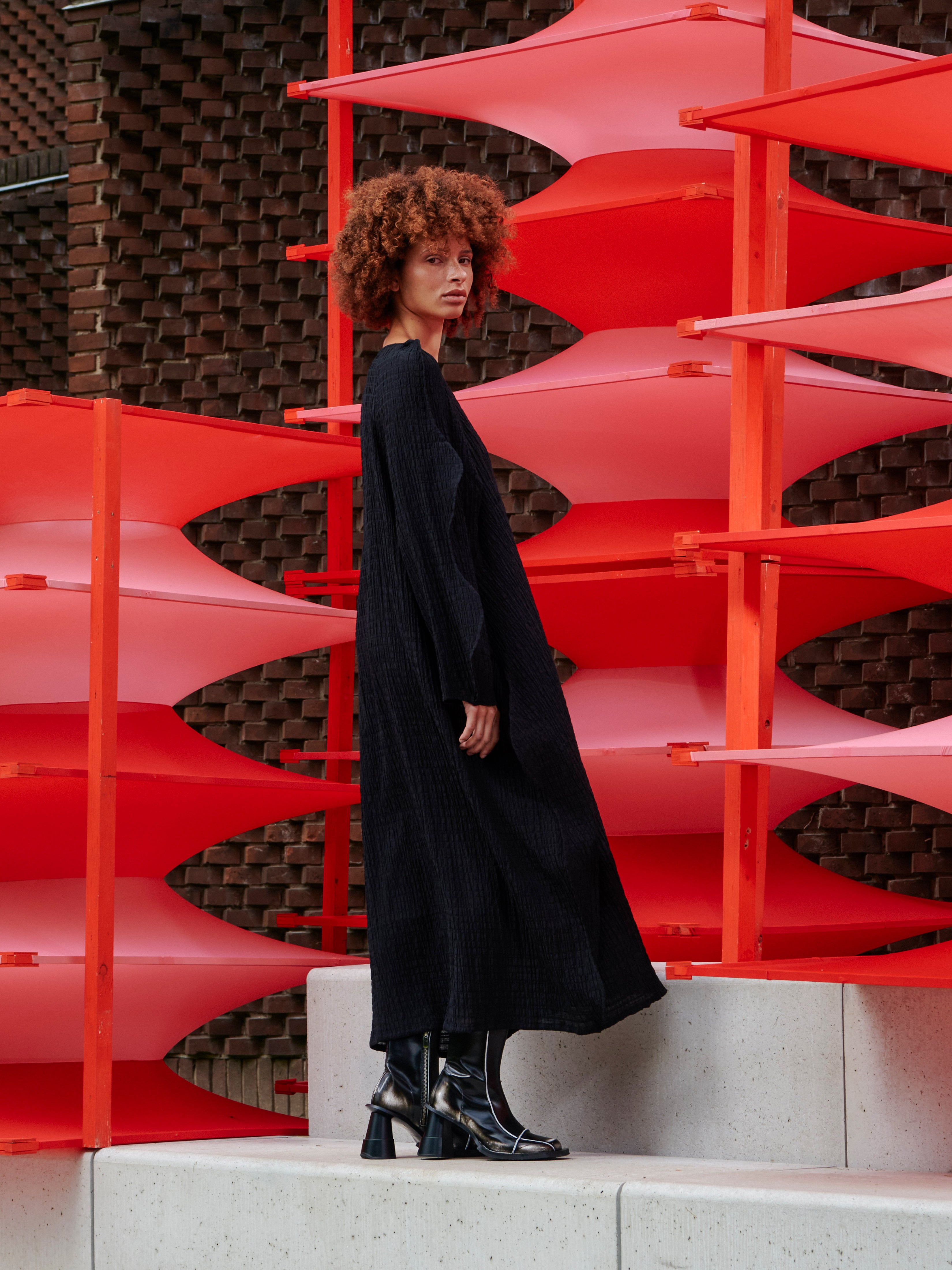 Model wearing the Octo Dress in Black black checkered dress with curved long sleeves and relaxed loose-fit silhouette, side view – Henrik Vibskov Spring/Summer 2026 Key Collection