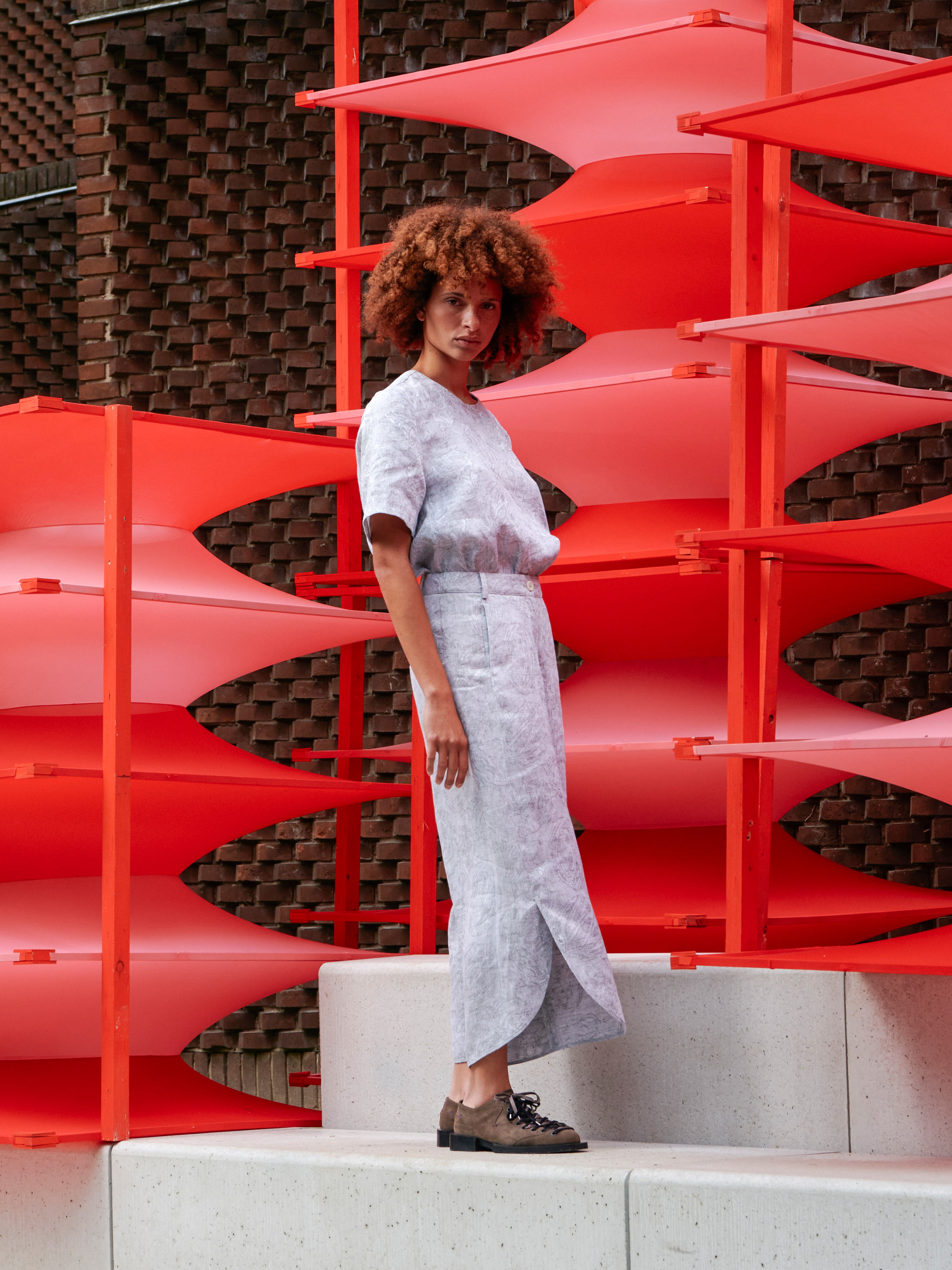 Side view of the model wearing the grey floral pants, emphasizing the curved hem and fluid drape.
