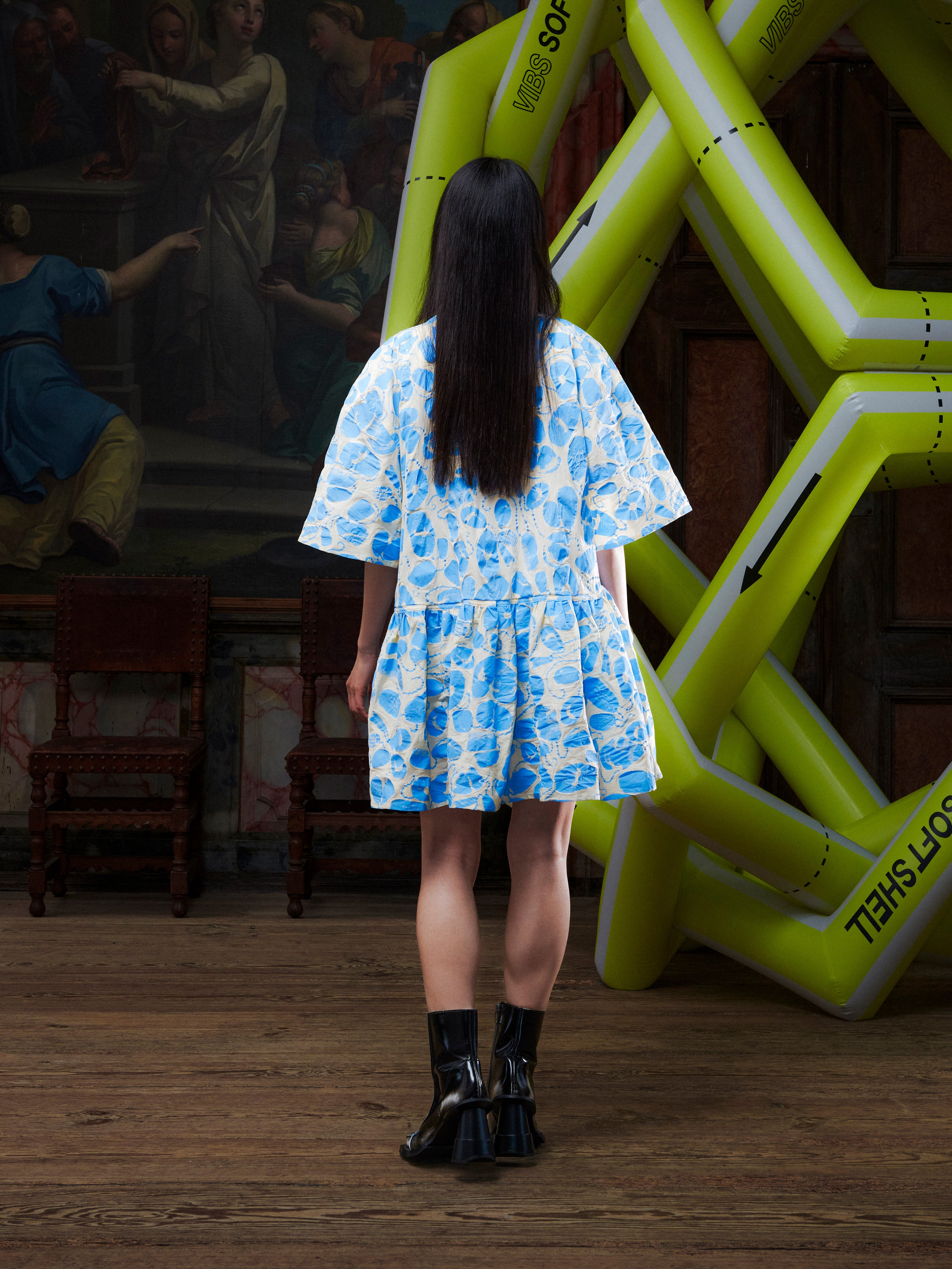 Model wearing the Henrik Vibskov Preserve Blouse in Ecru Amulets, back view, showing the full pattern, oversized shape, and wide, knee-length skirt.