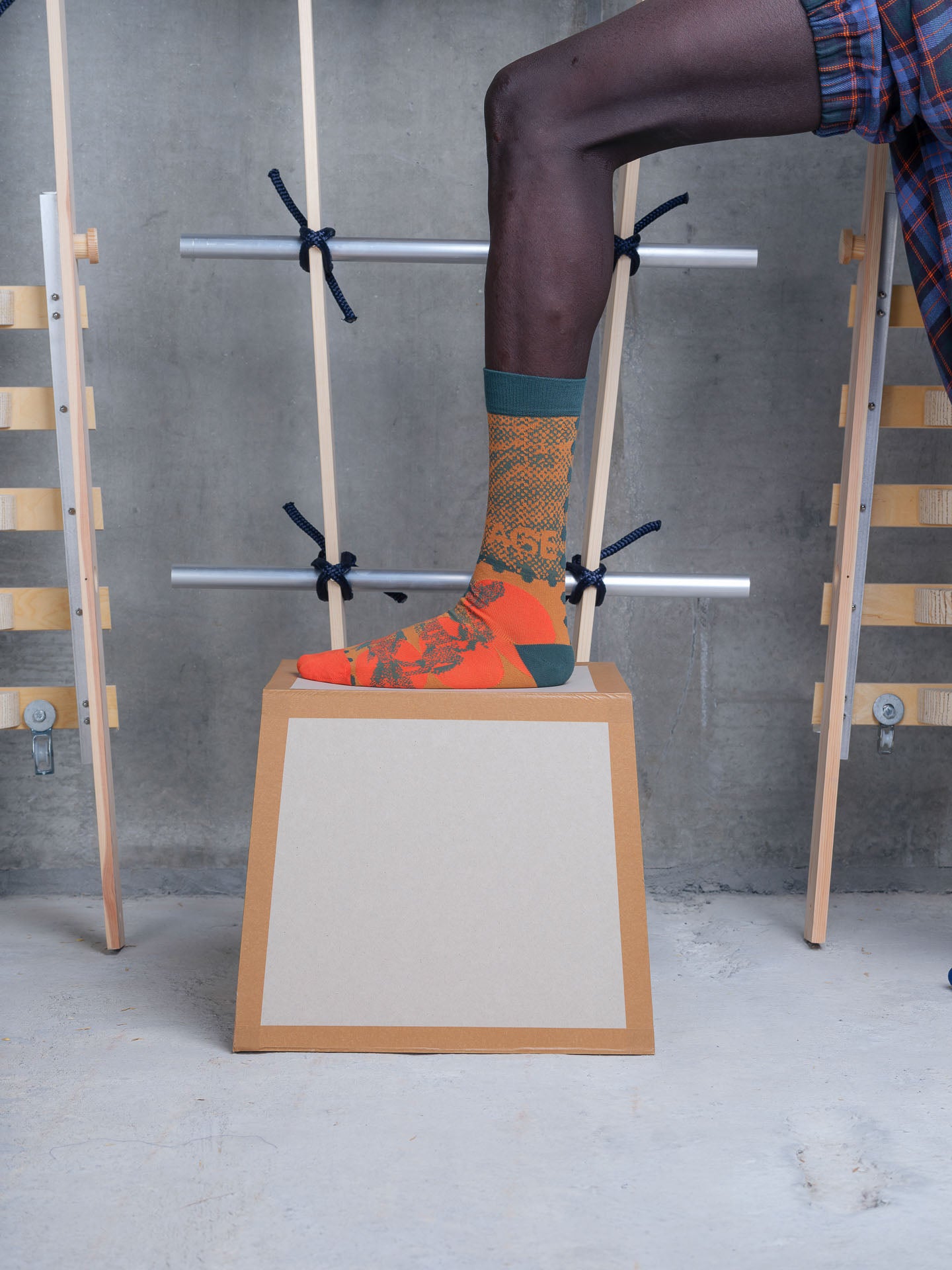 Model wearing the Henrik Vibskov Tower Sock in Postage Mandarin Dots, close-up side view