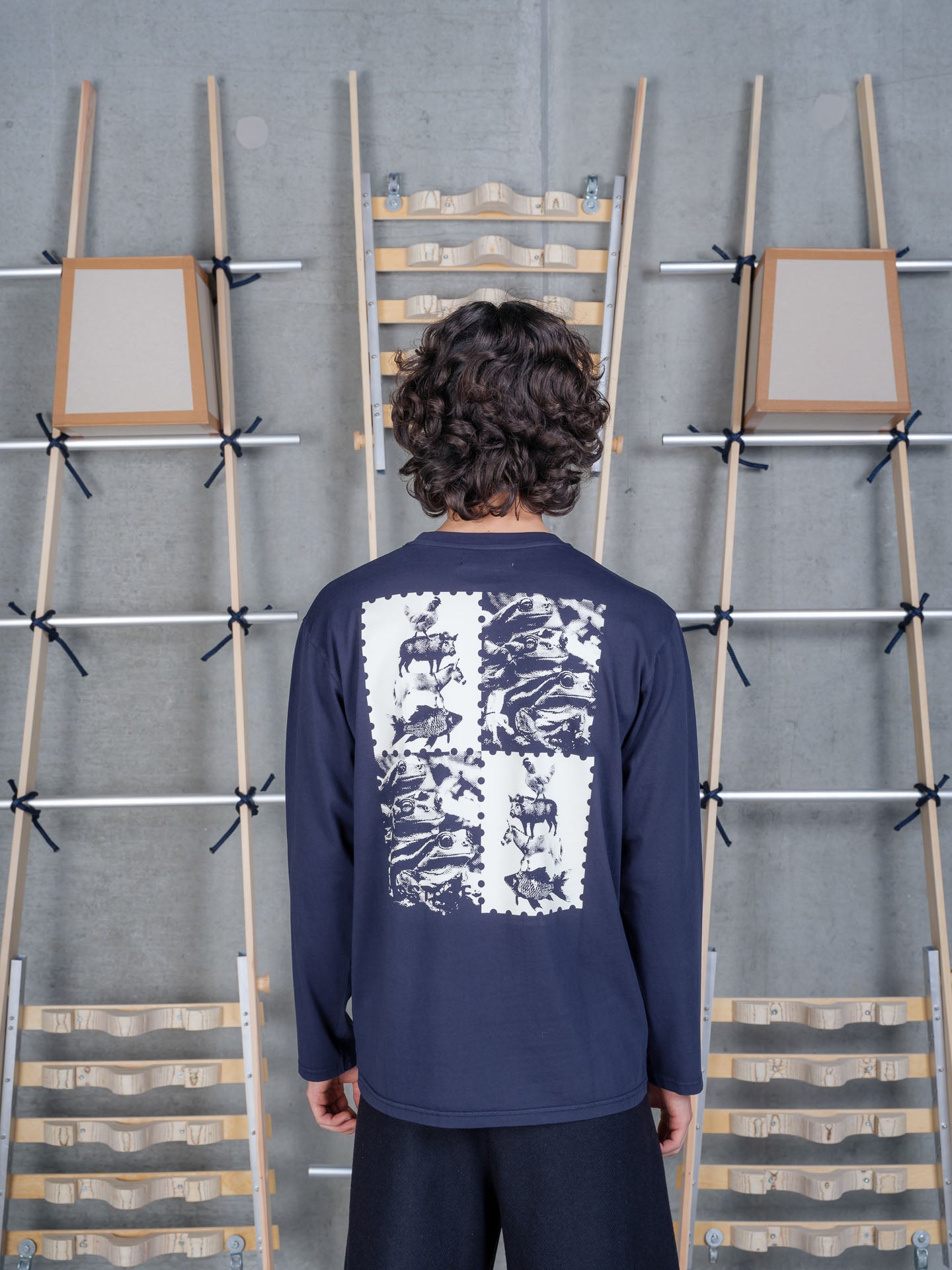 Back view of a male model wearing the Henrik Vibskov Tower Swamp Blouse in Black, featuring the bold back graphic print and easy-fitting crew neck silhouette.