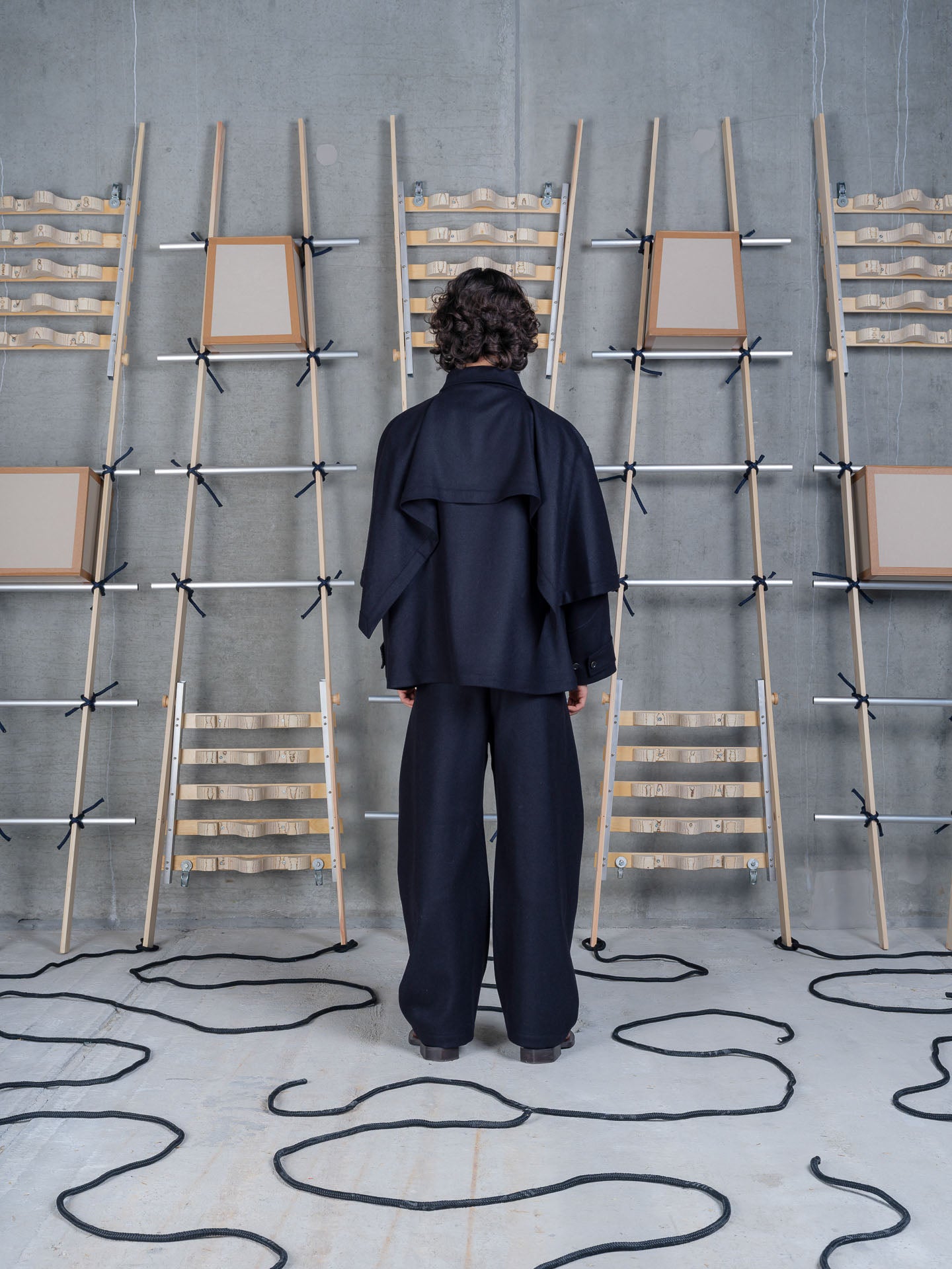 Henrik Vibskov Uncut Jacket Black, model rear three-quarter view, showing draped sleeve detail
