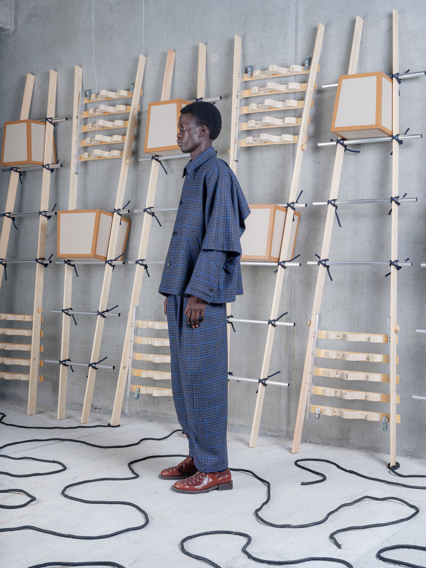 Henrik Vibskov Uncut Jacket Blue Wool Checks, model side view, showing dropped shoulder and cape-like volume