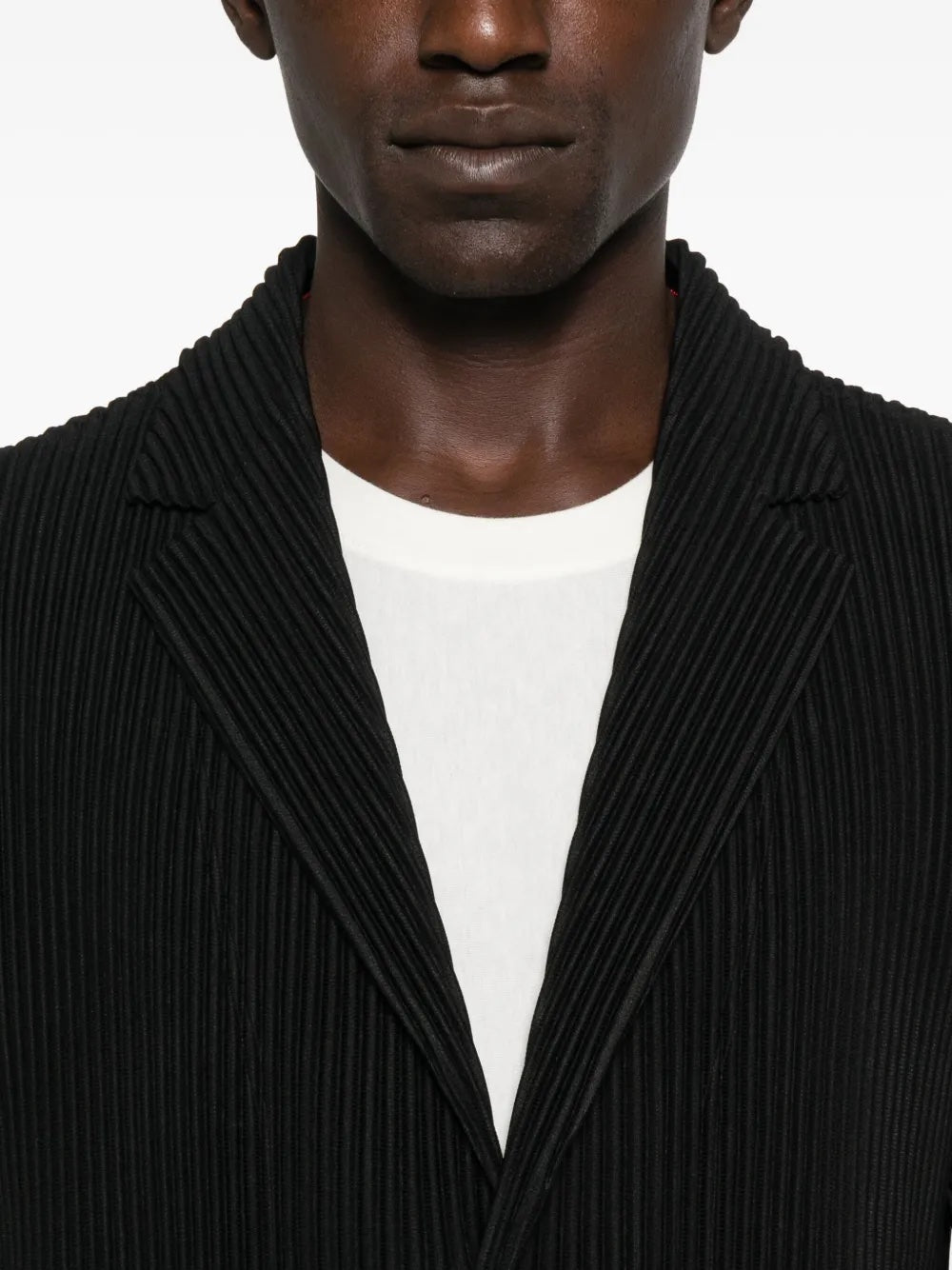 Man wearing a black ribbed blazer over a white shirt on a white background