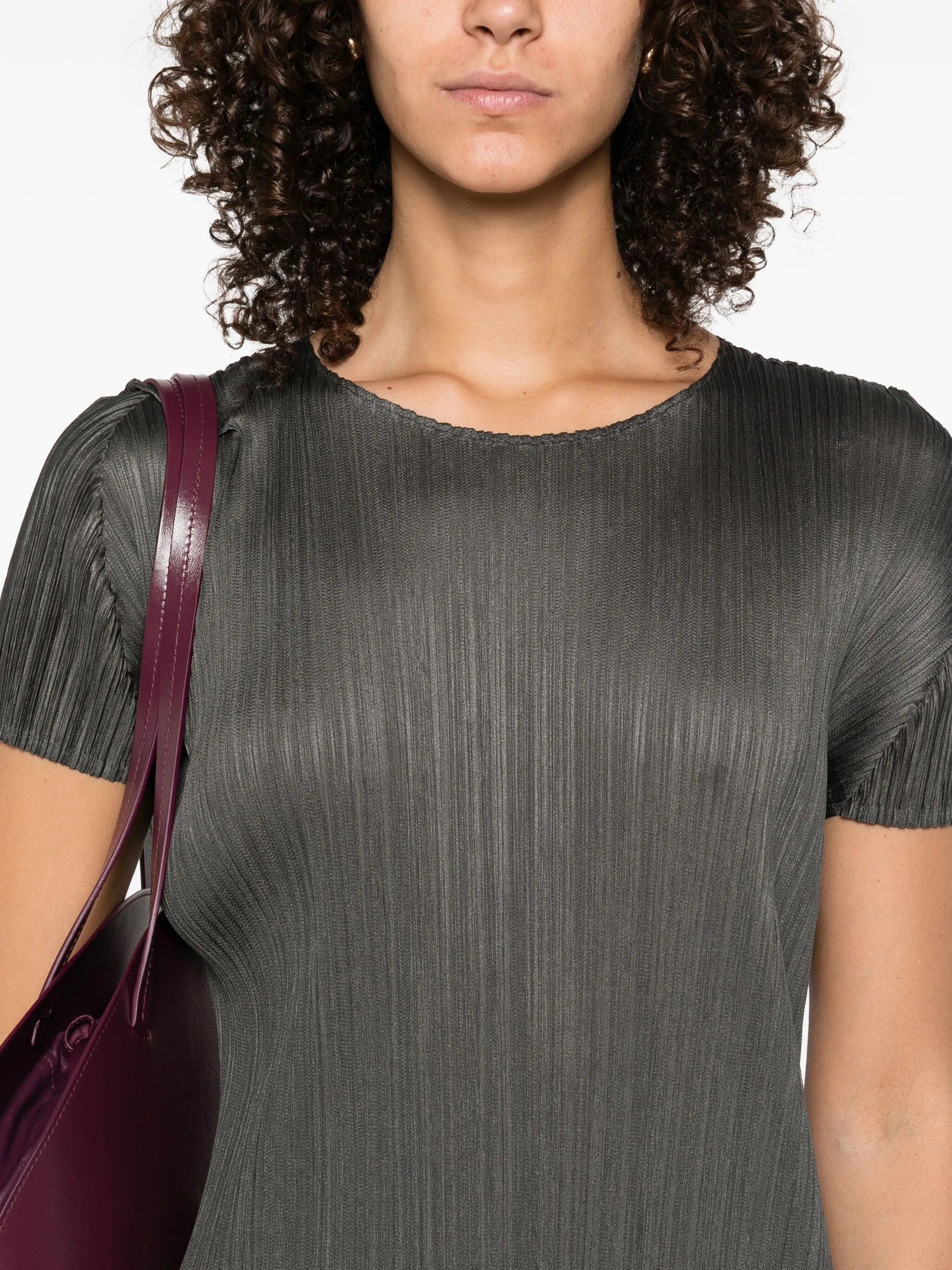 Woman wearing a gray pleated dress with a purple bag on a white background