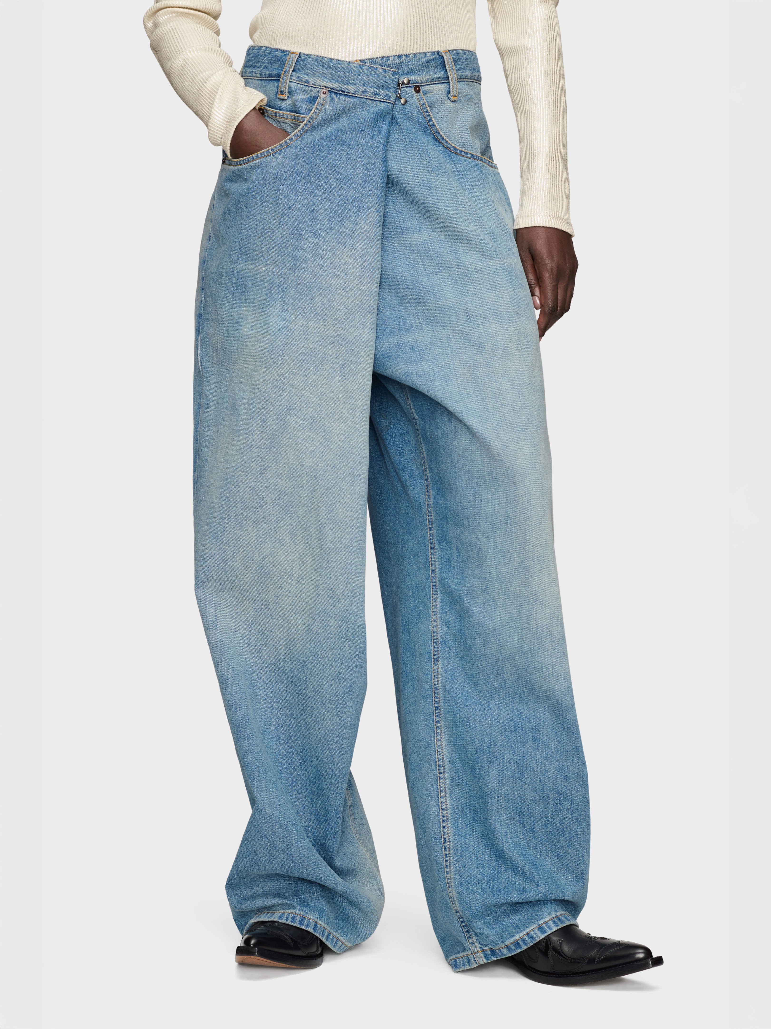 Model wearing the Maison Margiela 5-Pocket Pants in Old Blue, showing the relaxed wide-leg silhouette, asymmetric front and floor-length cut.