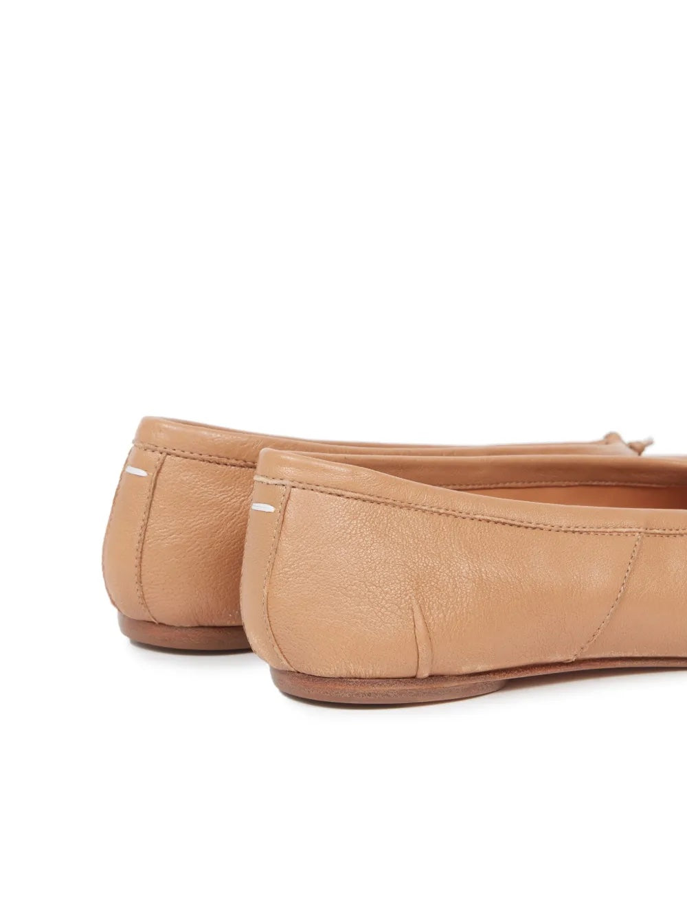 Pair of tan leather flats on a white background
