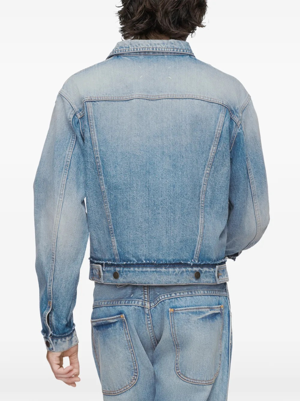 Close-up back view of the model wearing the washed blue denim Maison Margiela sports jacket, highlighting the faded denim texture and construction details.