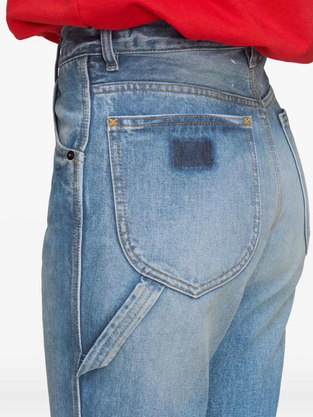 Diagonal back close-up of a female model wearing the Maison Margiela Pants 5 Pockets in Light Blue Indigo, showing the rear pocket construction, waistband, and smooth woven finish of the tailored trousers.