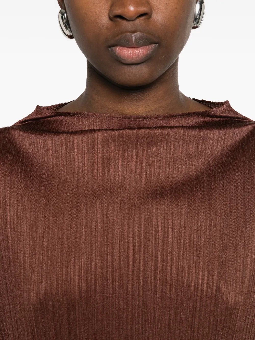 Close-up of the brown, long sleeve, pleated top by Pleats Please Issey Miyake on a white background