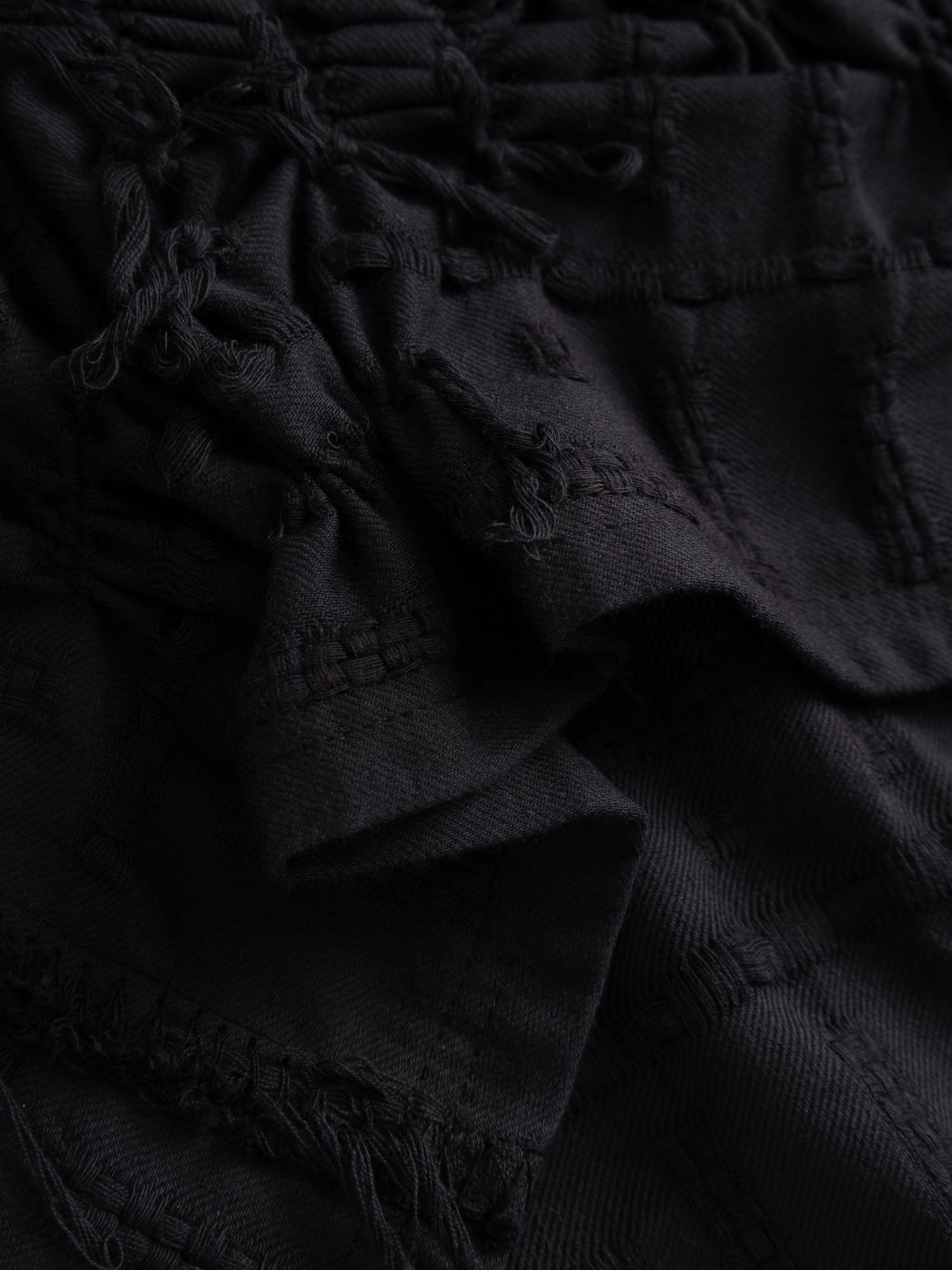 Stem Basket Tee in black, close-up of hand-knotted surface texture and zero-waste textile construction detail