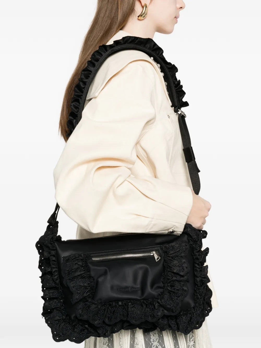 Model wearing the black Pillowcase Shoulder Bag, showing the softly structured nylon shape, ruffled strap, and embroidered daisy detail.