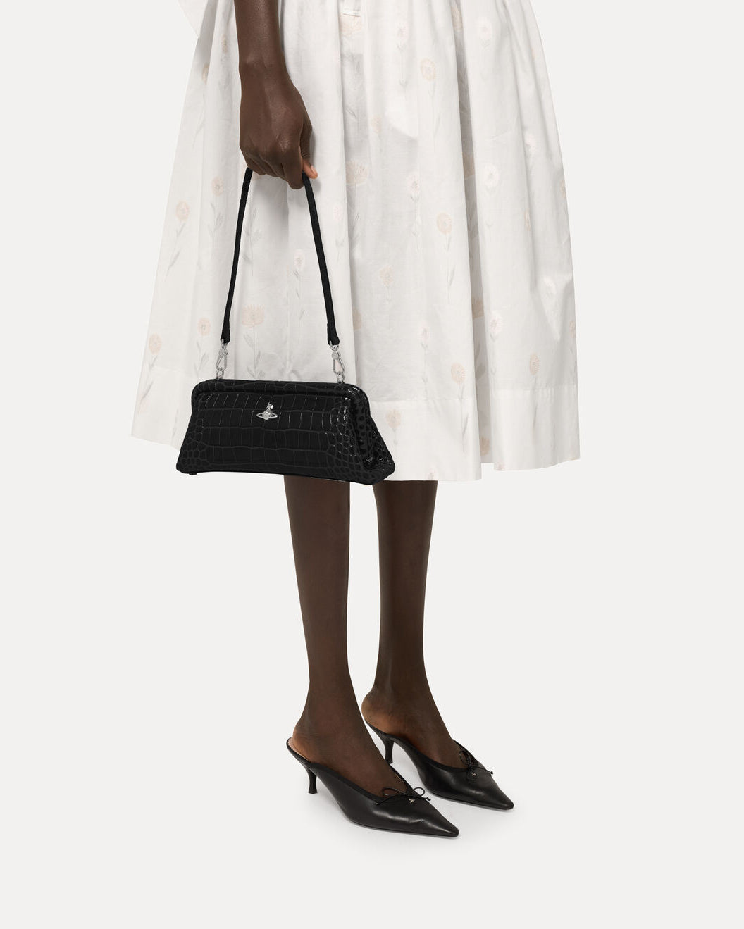 Vivienne Westwood Jane Frame Purse in Black styled on model, carried with the detachable strap against a white outfit.