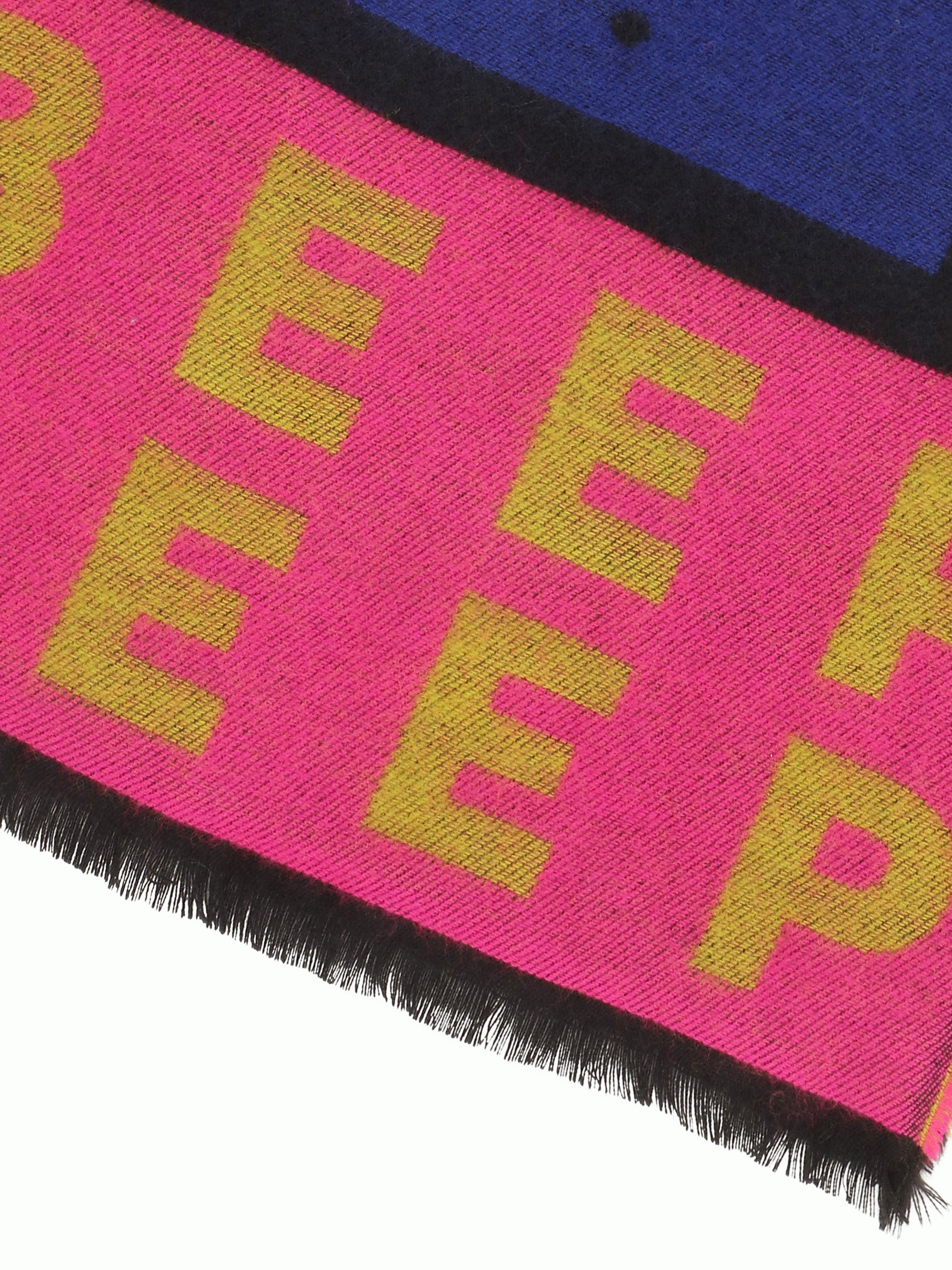 Close-up of a pink scarf from Walter Van Beirendonck with yellow text on a white background