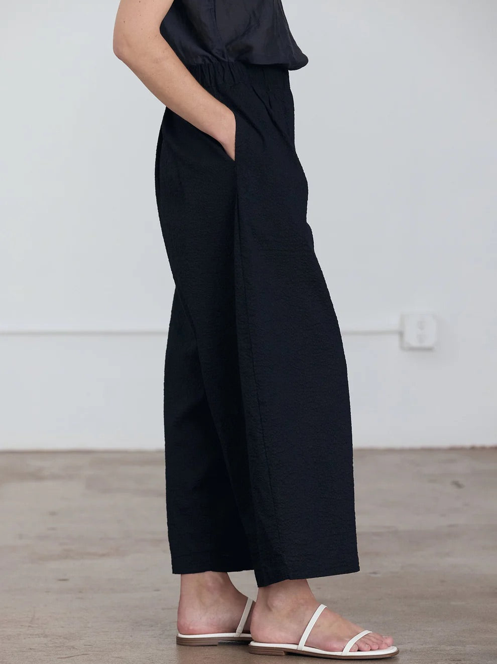 Black Crane Wide Pants in Midnight - three-quarter view on model showing wide silhouette and ripple textured fabric