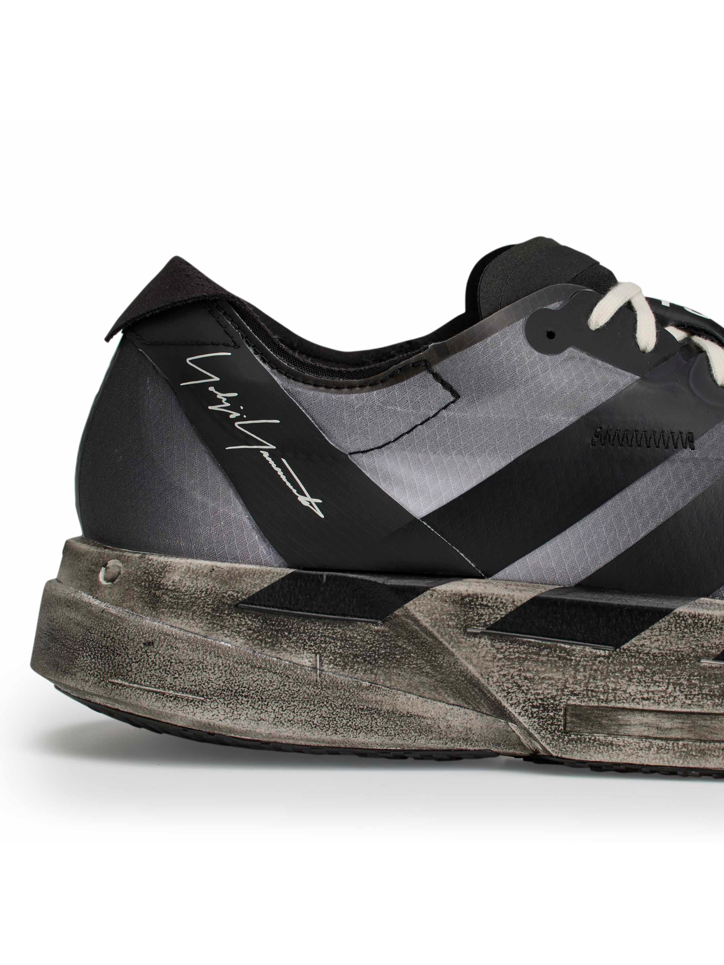 Y-3 Adios Pro 4 close-up side view, tonal 3-Stripes on black synthetic upper, off-white rope laces, worn midsole texture detail