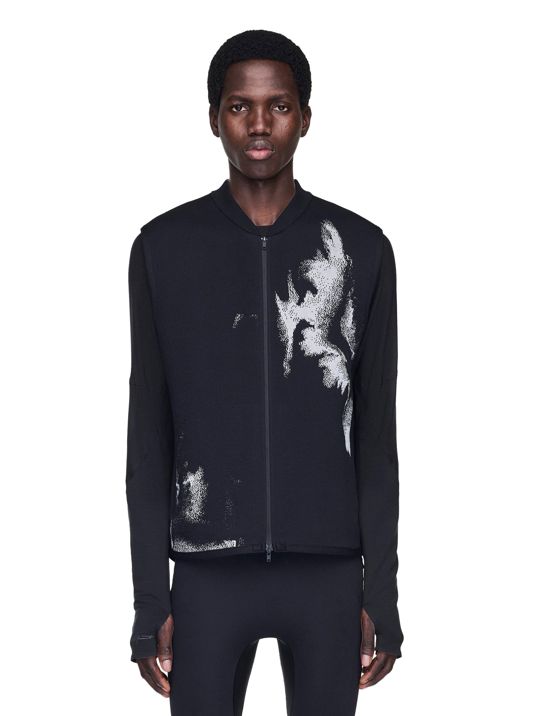 Person wearing a black vest with white abstract design on a white background