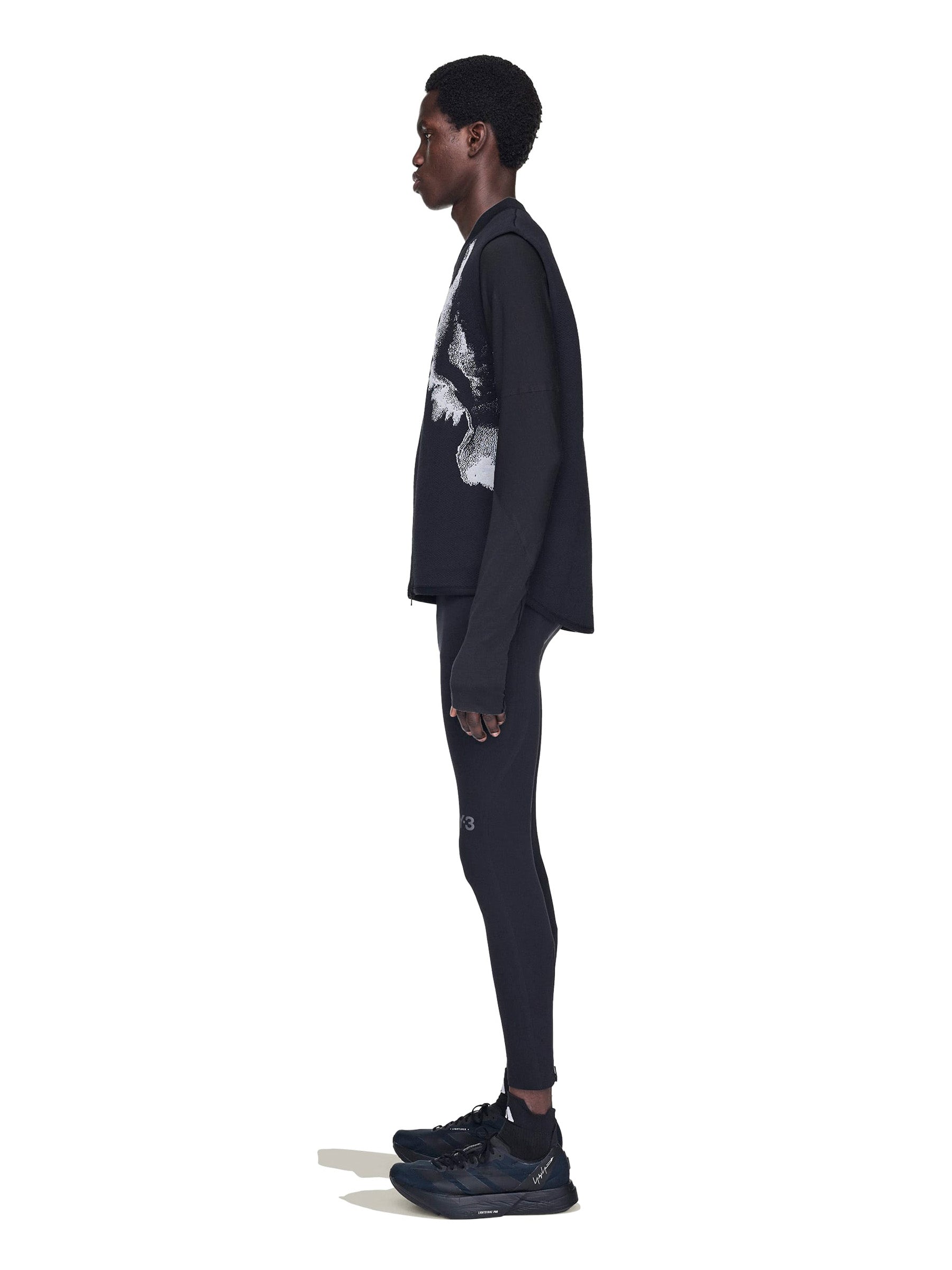 Person wearing a dark outfit with a white logo on a white background