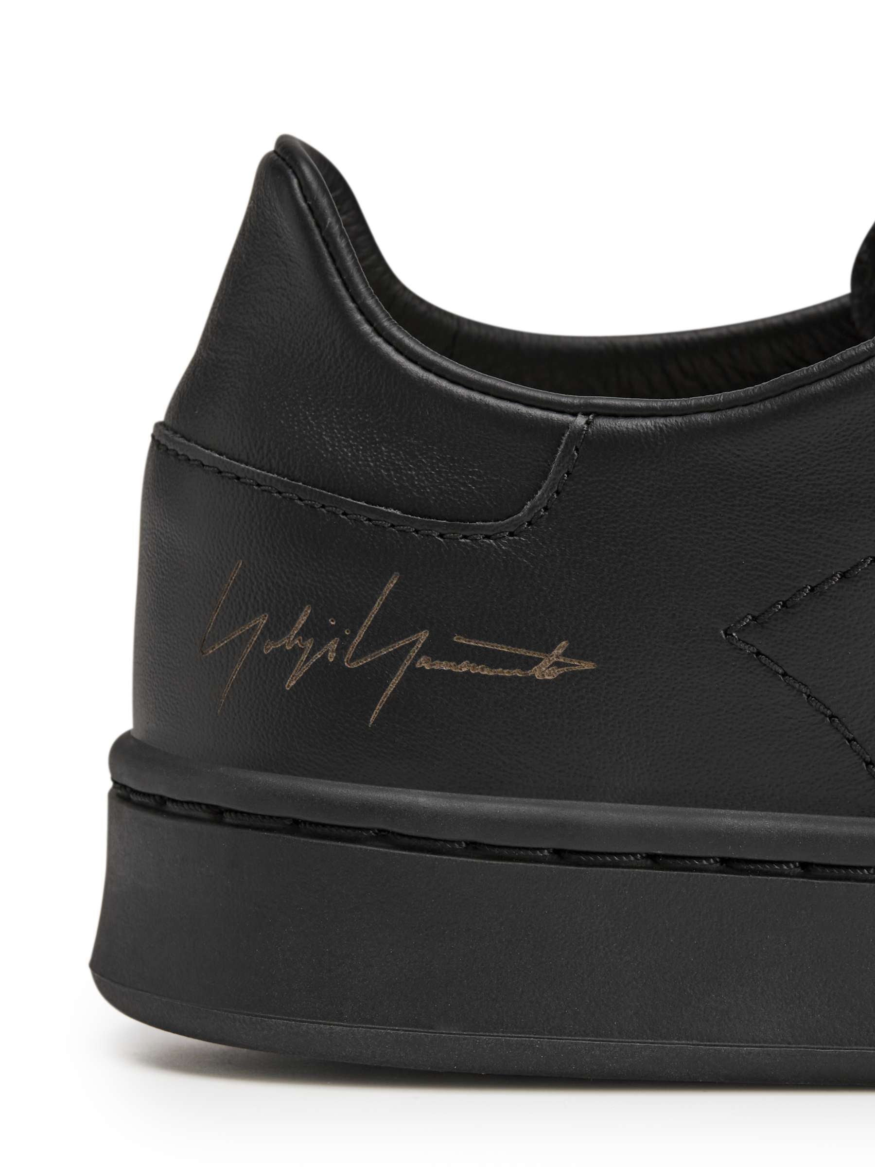 Side view close-up of the heel of the Y-3 Stan Smith Hook-and-Loop Shoes in Black, showing the Yohji Yamamoto signature and leather construction.