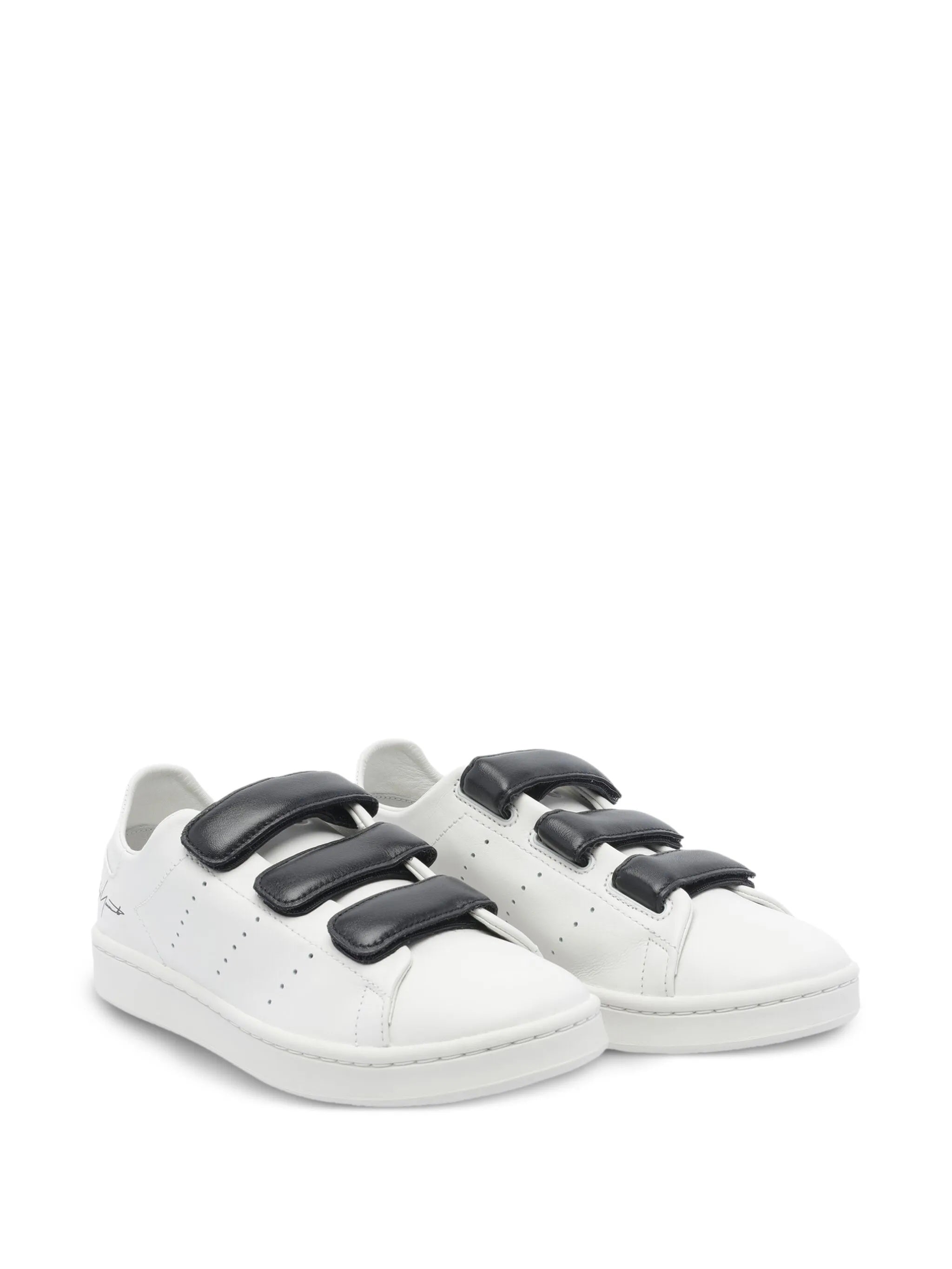 White sneakers with black velcro straps on a white background