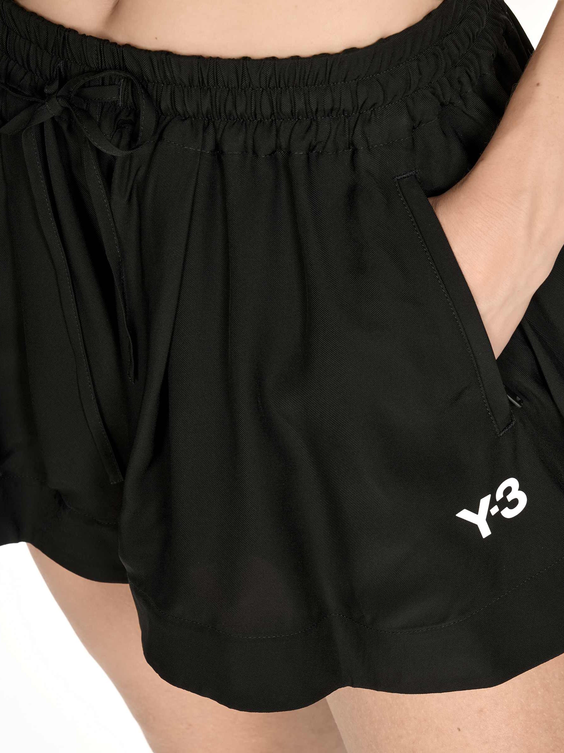 Close-up of the front of the Y-3 Women’s Tennis Shorts in Black on a model, showing the fabric texture and minimalist craftsmanship.