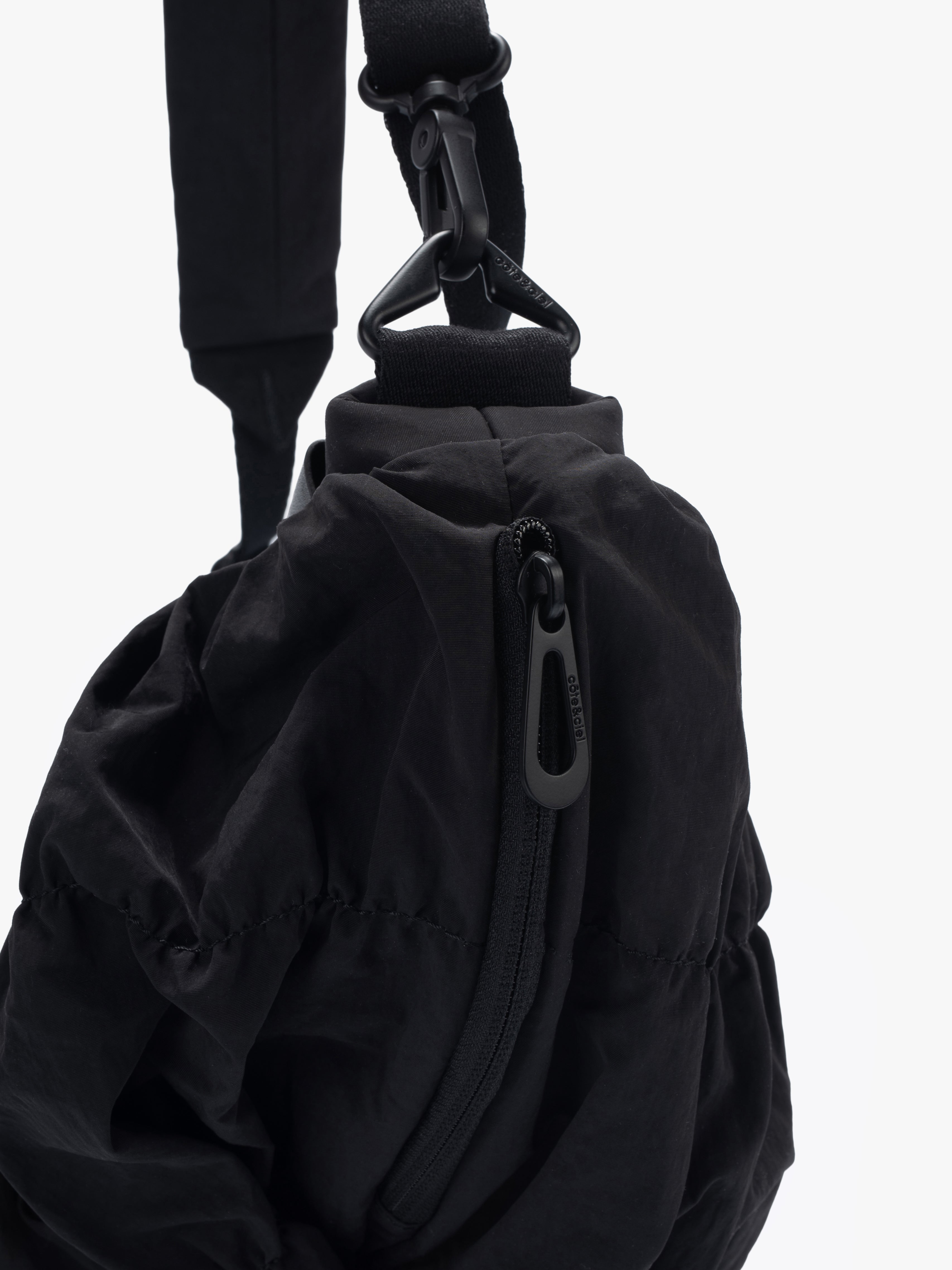 Closeup of Côte&Ciel Orne Otra Gathered black bag, showing water-repellent main compartment zipper and gathered nylon texture.