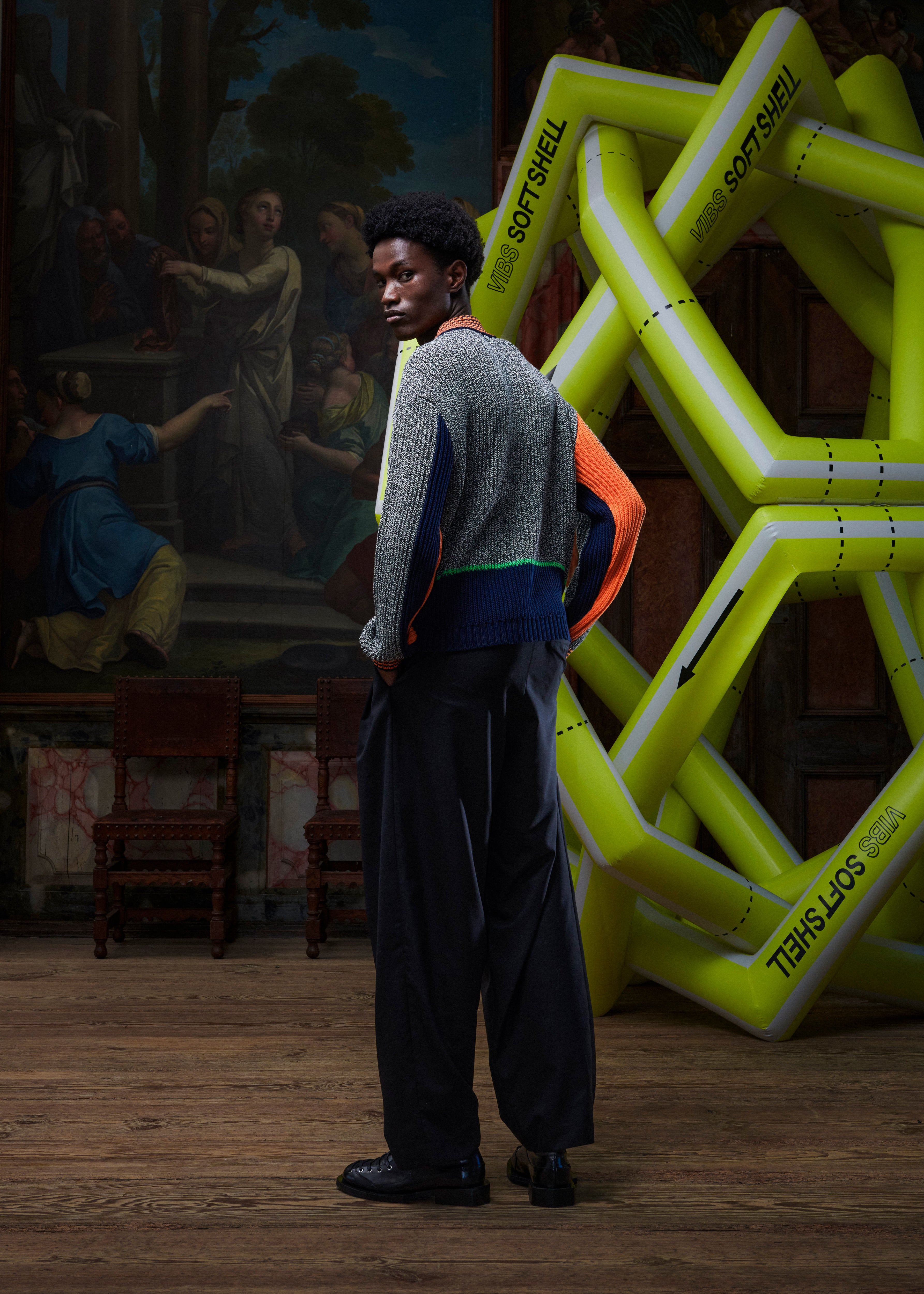 Back view of the male model wearing the Abundance Cardigan, displaying the color-blocked black, white, and navy design and straight hem