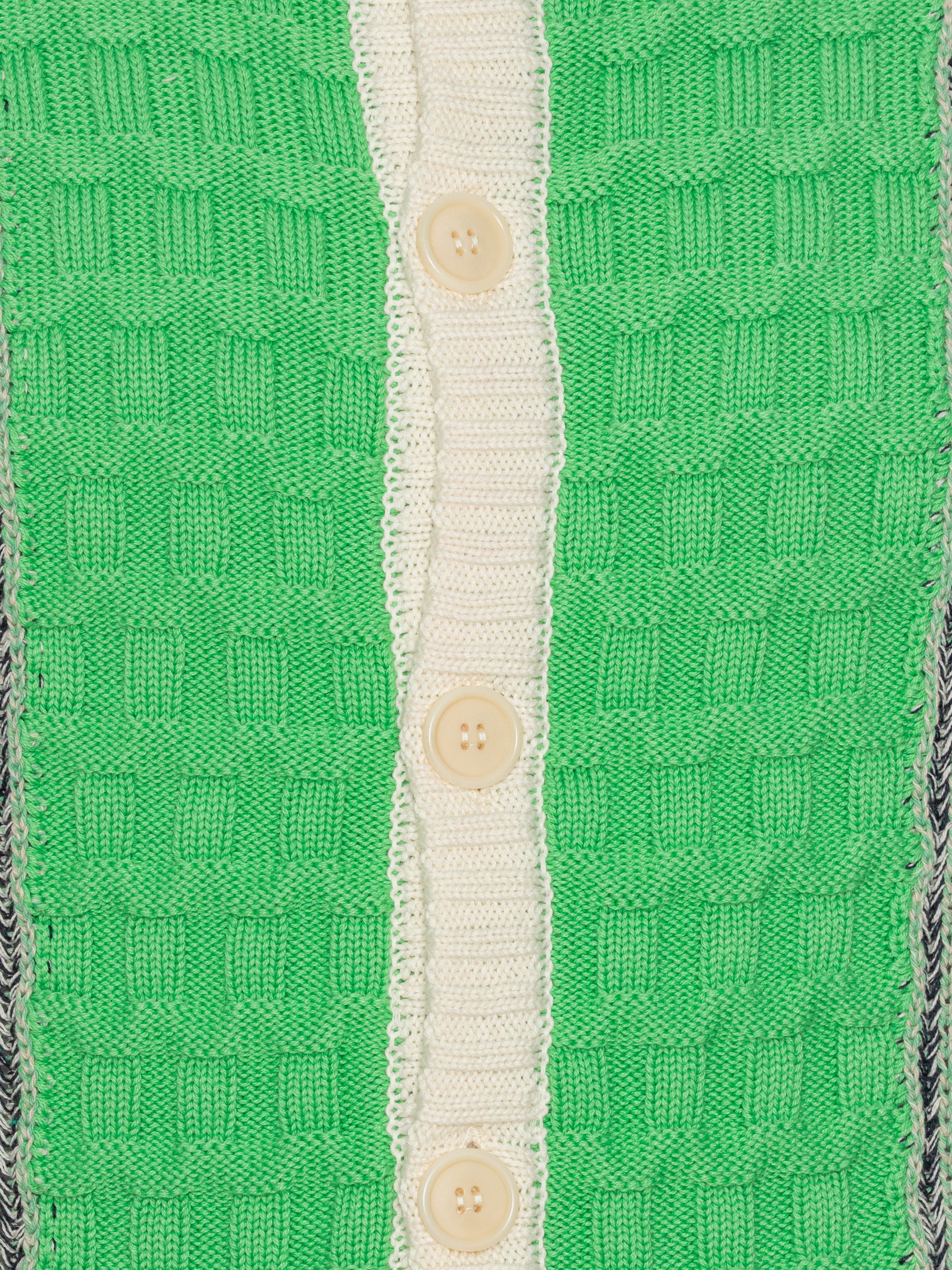 Close-up of the Abundance Cardigan from Henrik Vibskov Spring/Summer 2026 Studio Collection, showing the green, grey, and navy block design with beige details and textured knit around the button closure.