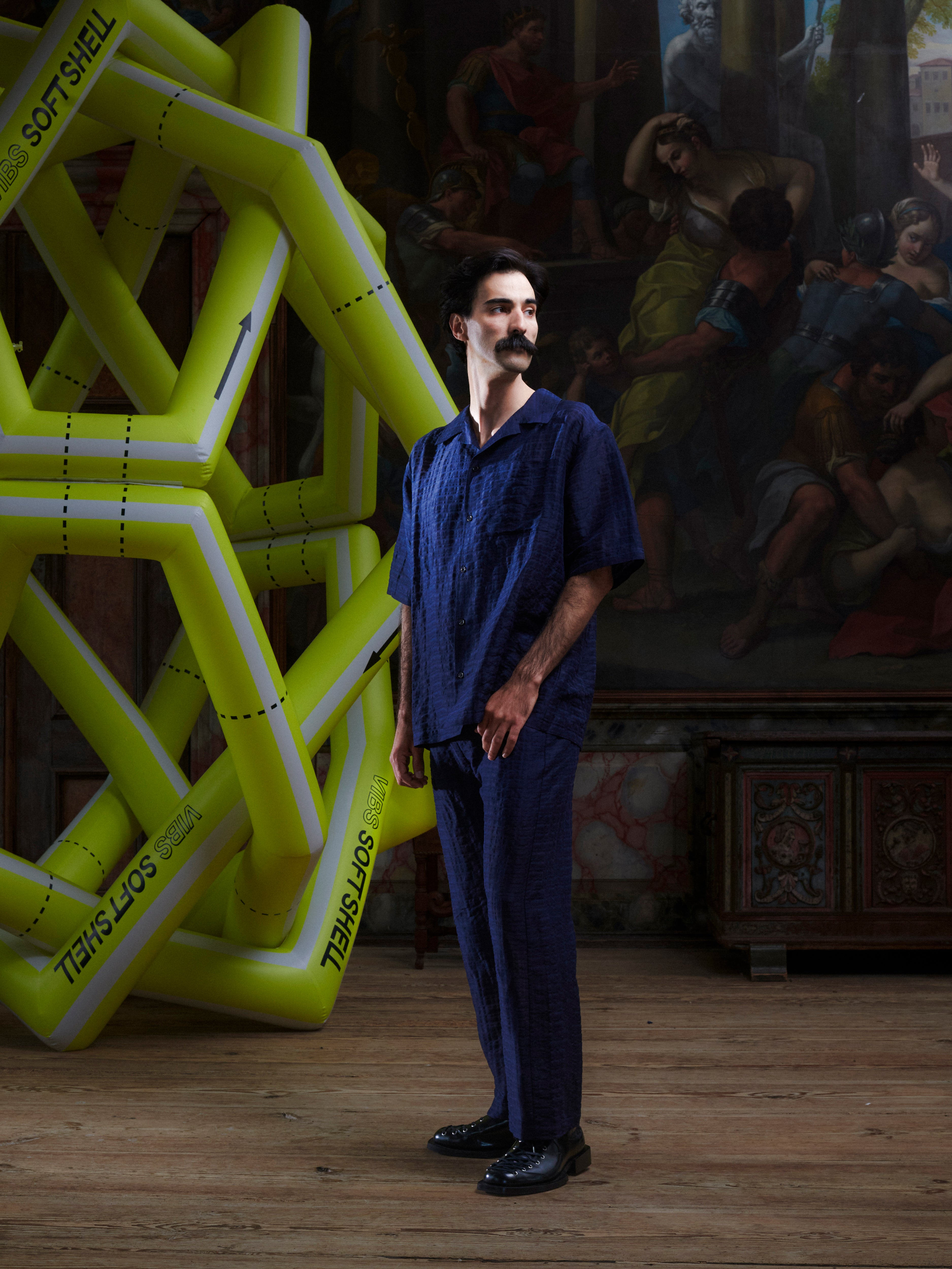 Side view of the male model wearing the Artist Pants in navy from Henrik Vibskov Spring/Summer 2026 Studio Collection, displaying the straight silhouette and pocket placement.